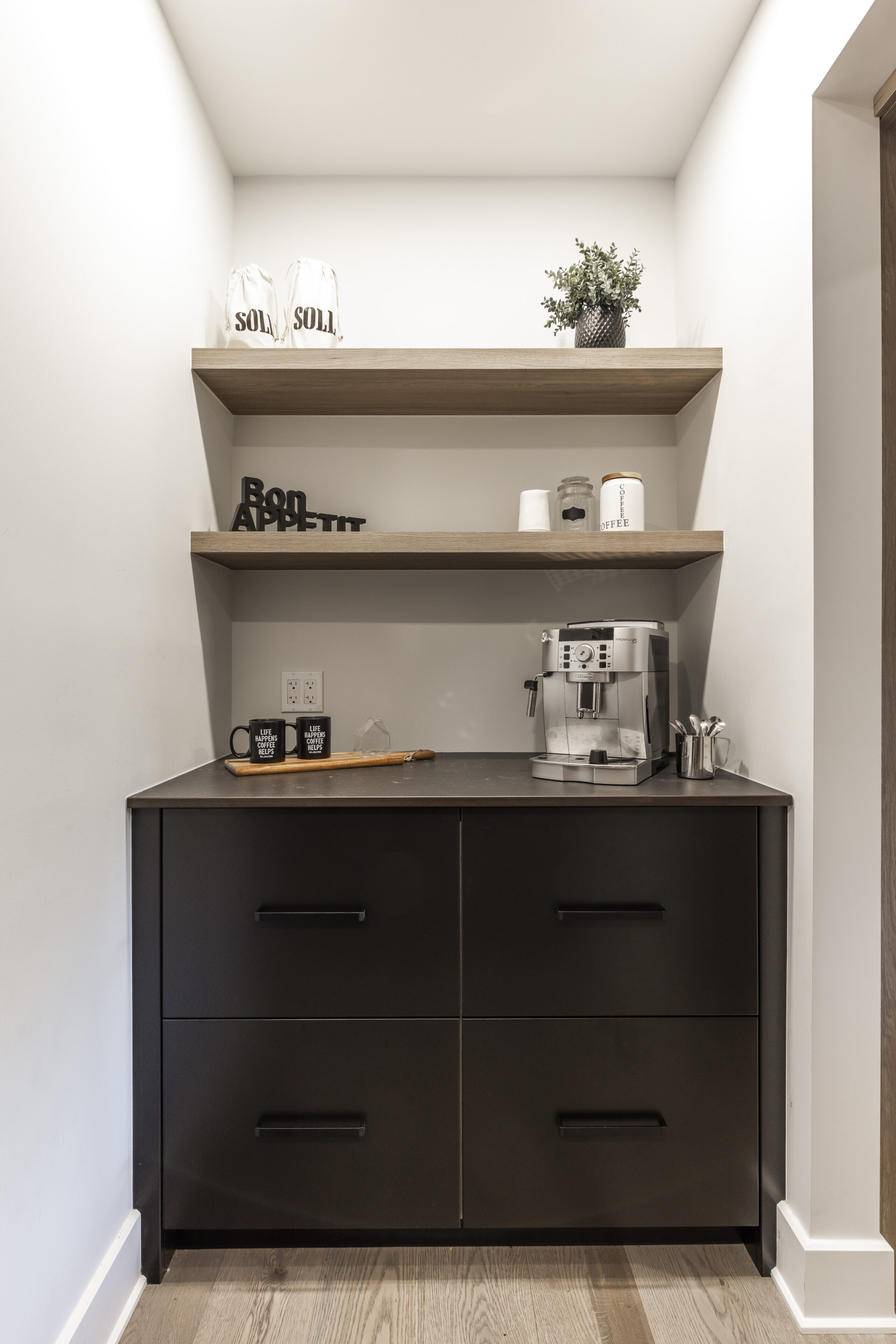 Modern coffee nook featuring a sleek black cabinet, light wood shelves, and inviting decor for a cozy beverage experience.