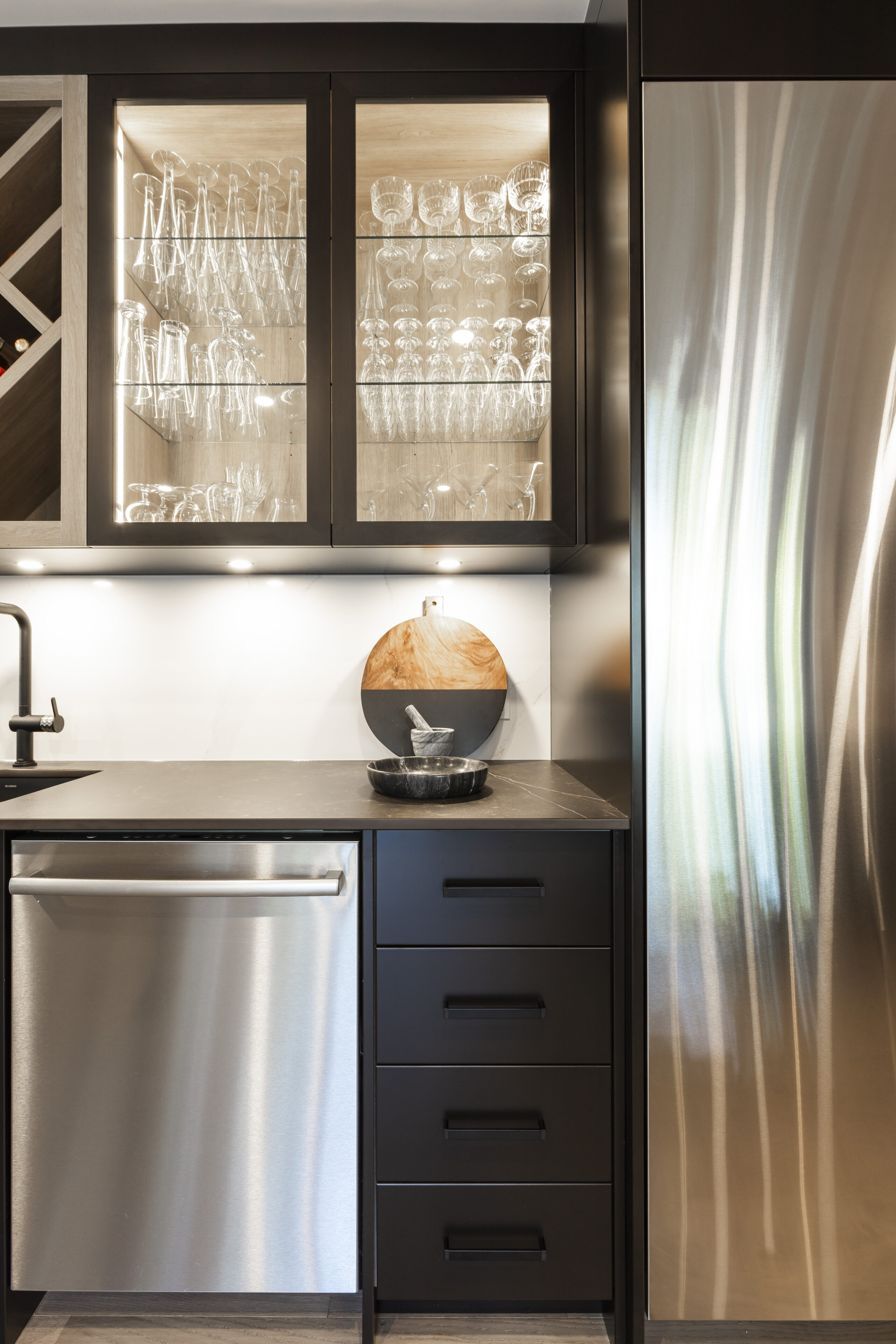 Discover a sophisticated modern kitchen featuring dark wood cabinetry, sleek stainless steel appliances, and elegant decorative accents.