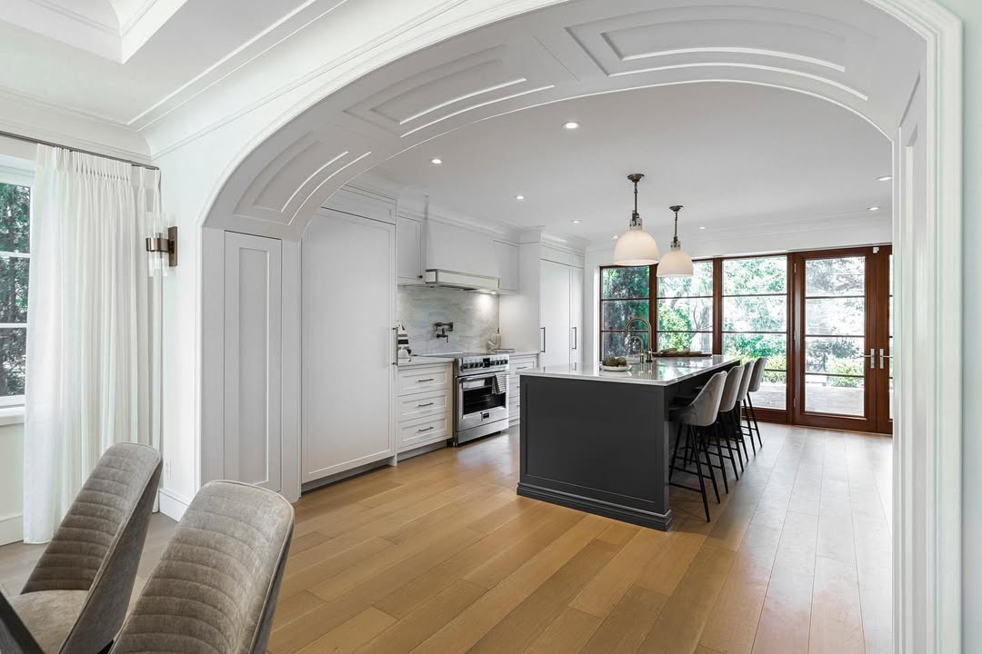 Bright and sophisticated modern kitchen featuring a dark gray island, stainless steel appliances, and abundant natural light.