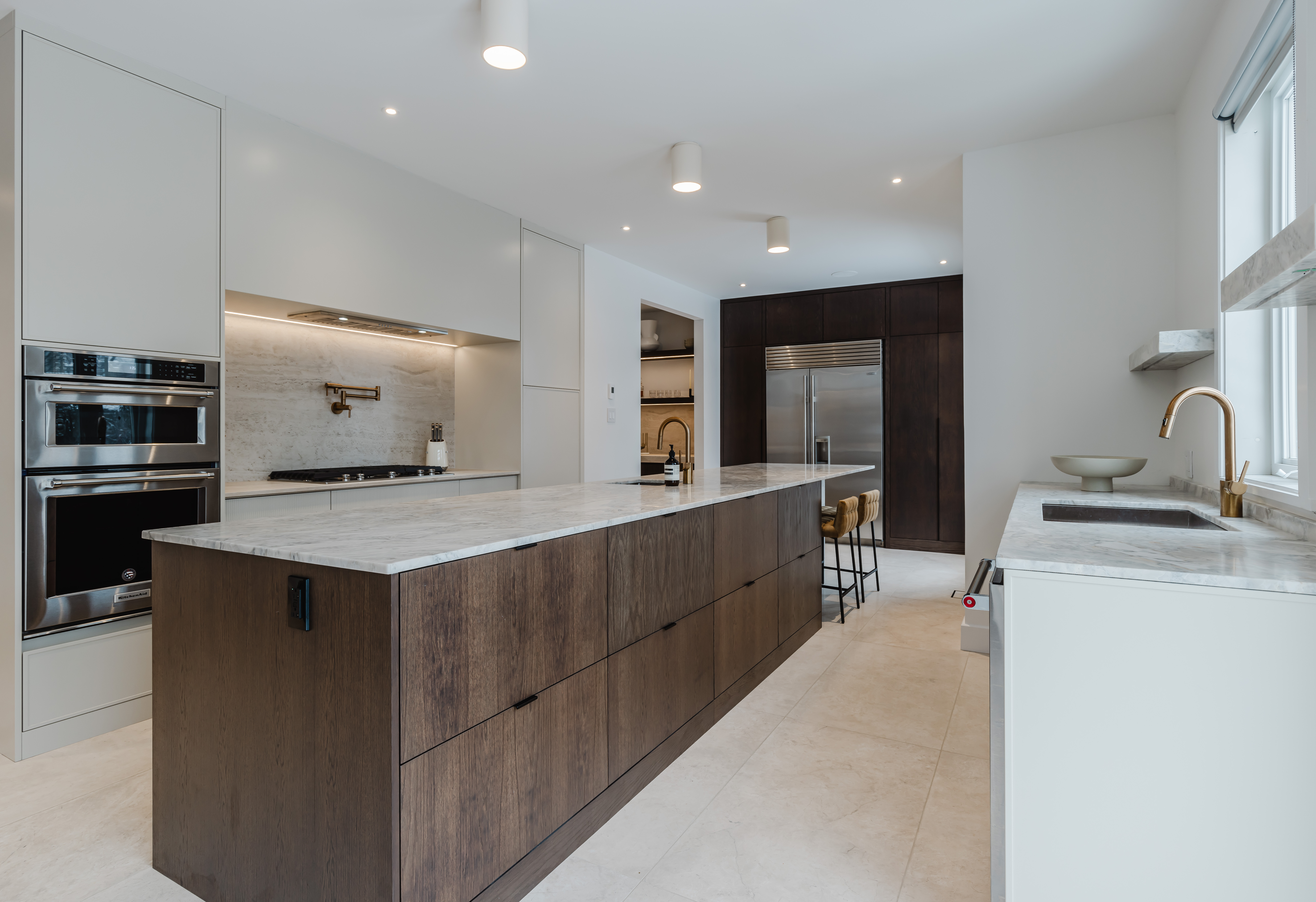 A stunning modern kitchen featuring a dark wood island, light cabinetry, and ample natural light for an inviting cooking and entertaining space.