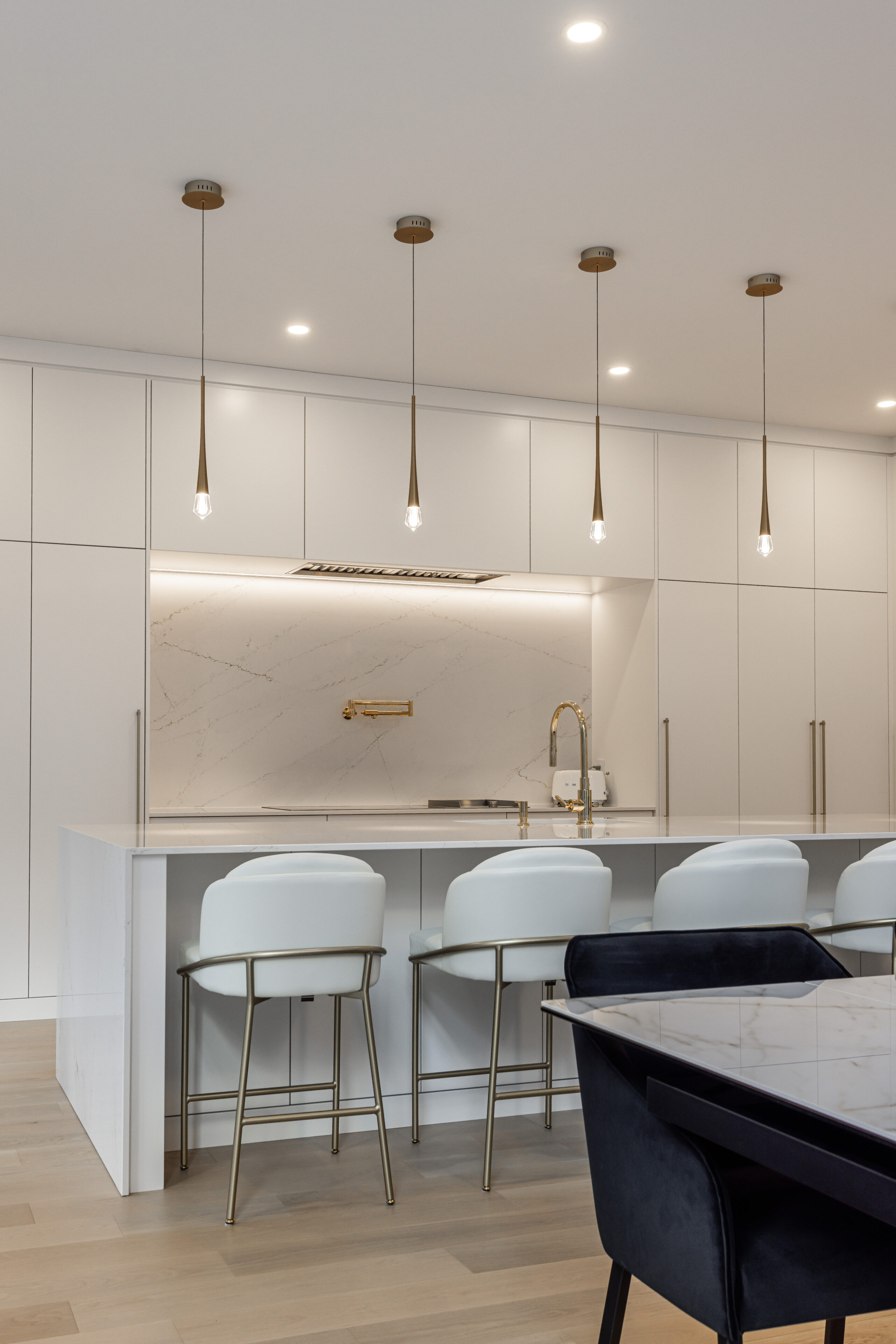 Elegant modern kitchen featuring light cabinetry, a spacious quartz island, and warm wood flooring for a cozy yet stylish atmosphere.