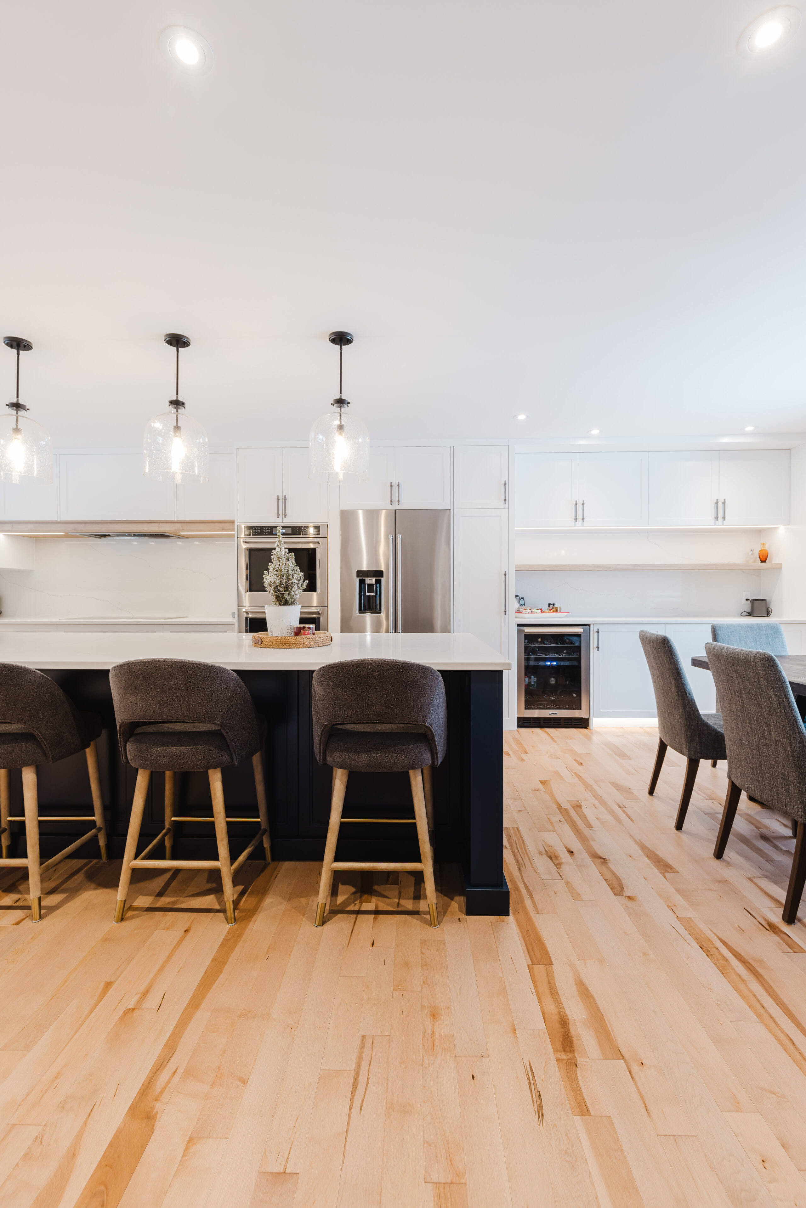 Stylish modern kitchen featuring a sleek white marble island, dark gray barstools, and a bright dining area perfect for gatherings.