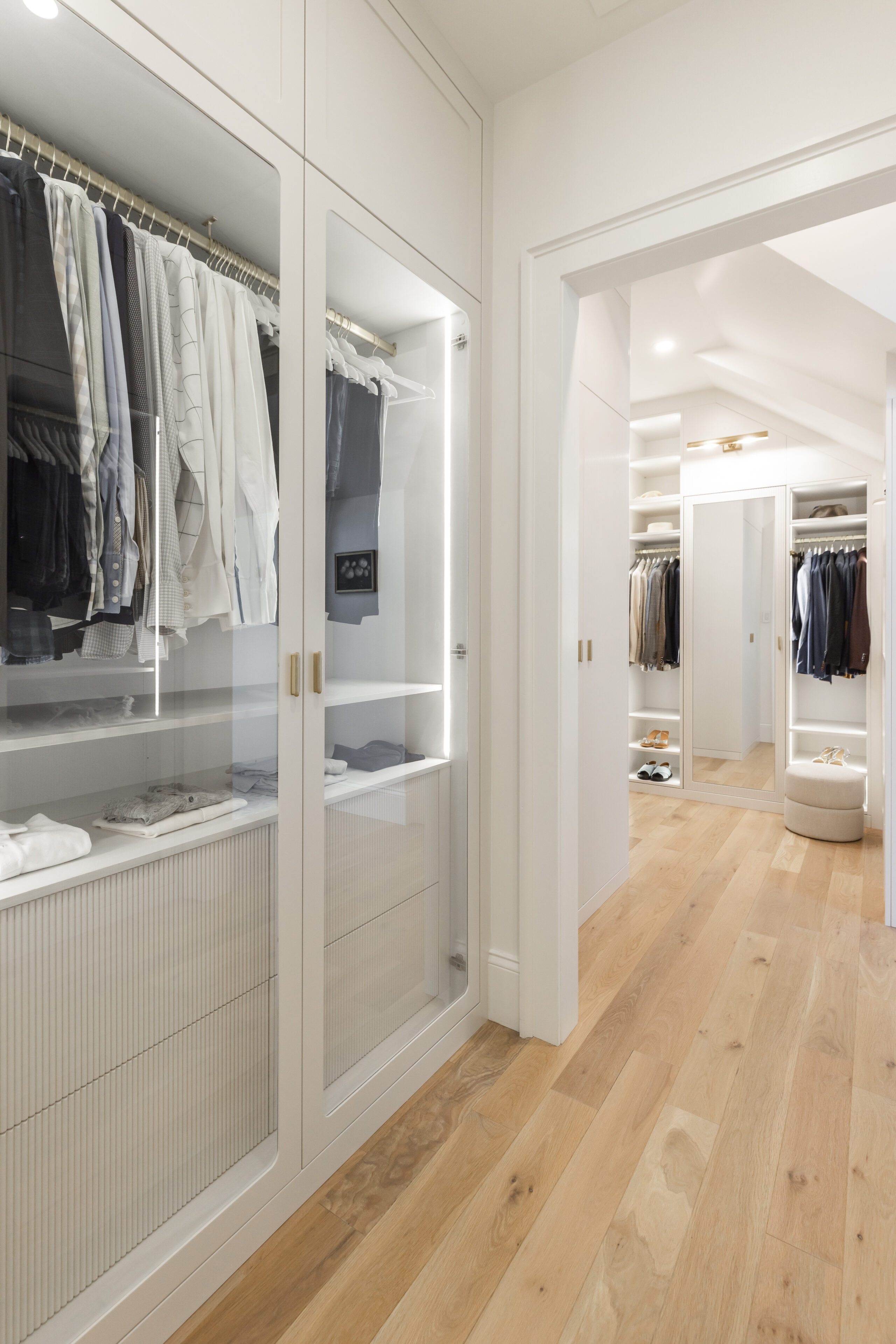 Discover a stylish modern closet featuring organized light clothing, warm wood floors, and a serene ambiance for the perfect fashion retreat.