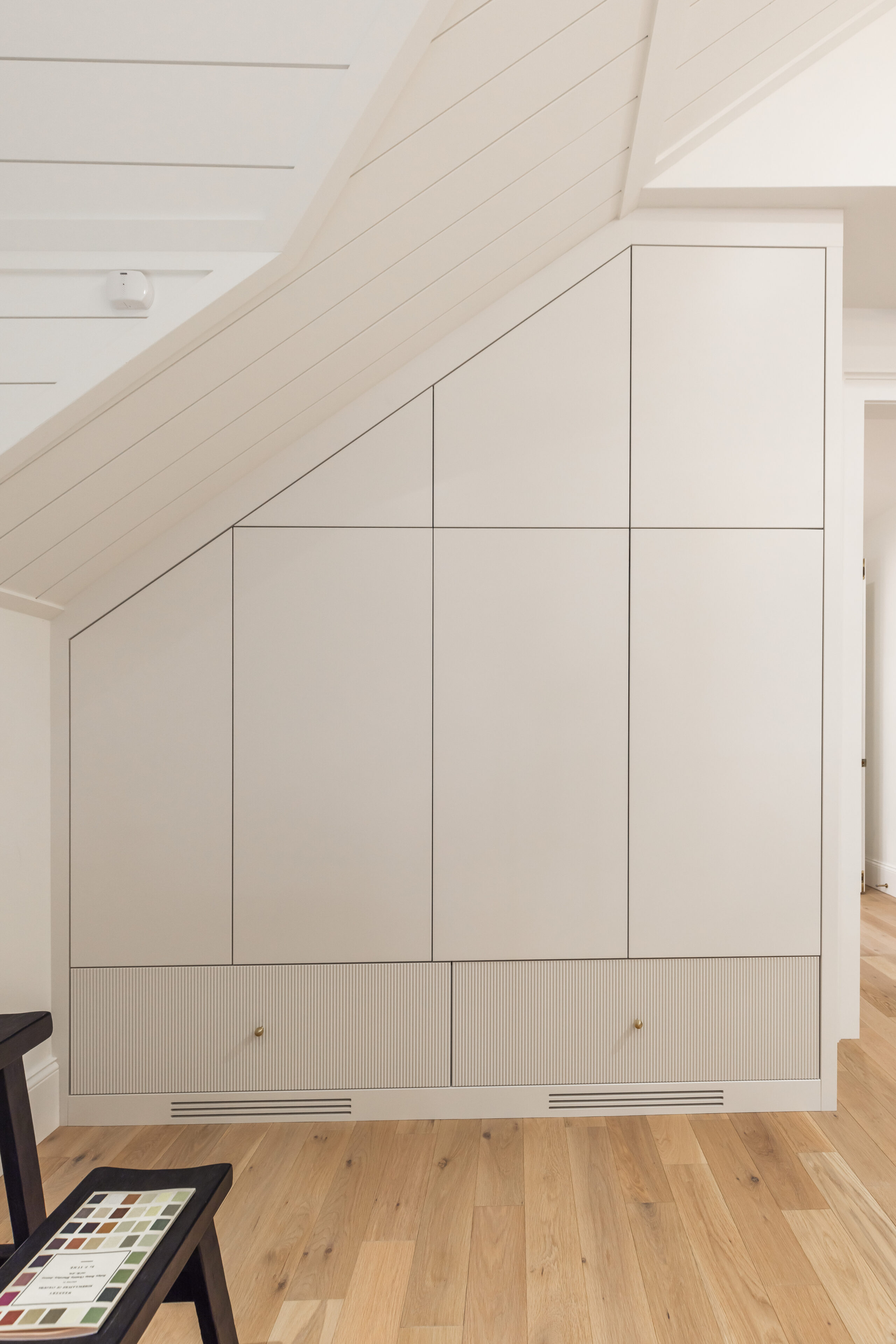 Sleek minimalist cabinetry under a sloped ceiling maximizes storage while enhancing the rooms light and airy ambiance.