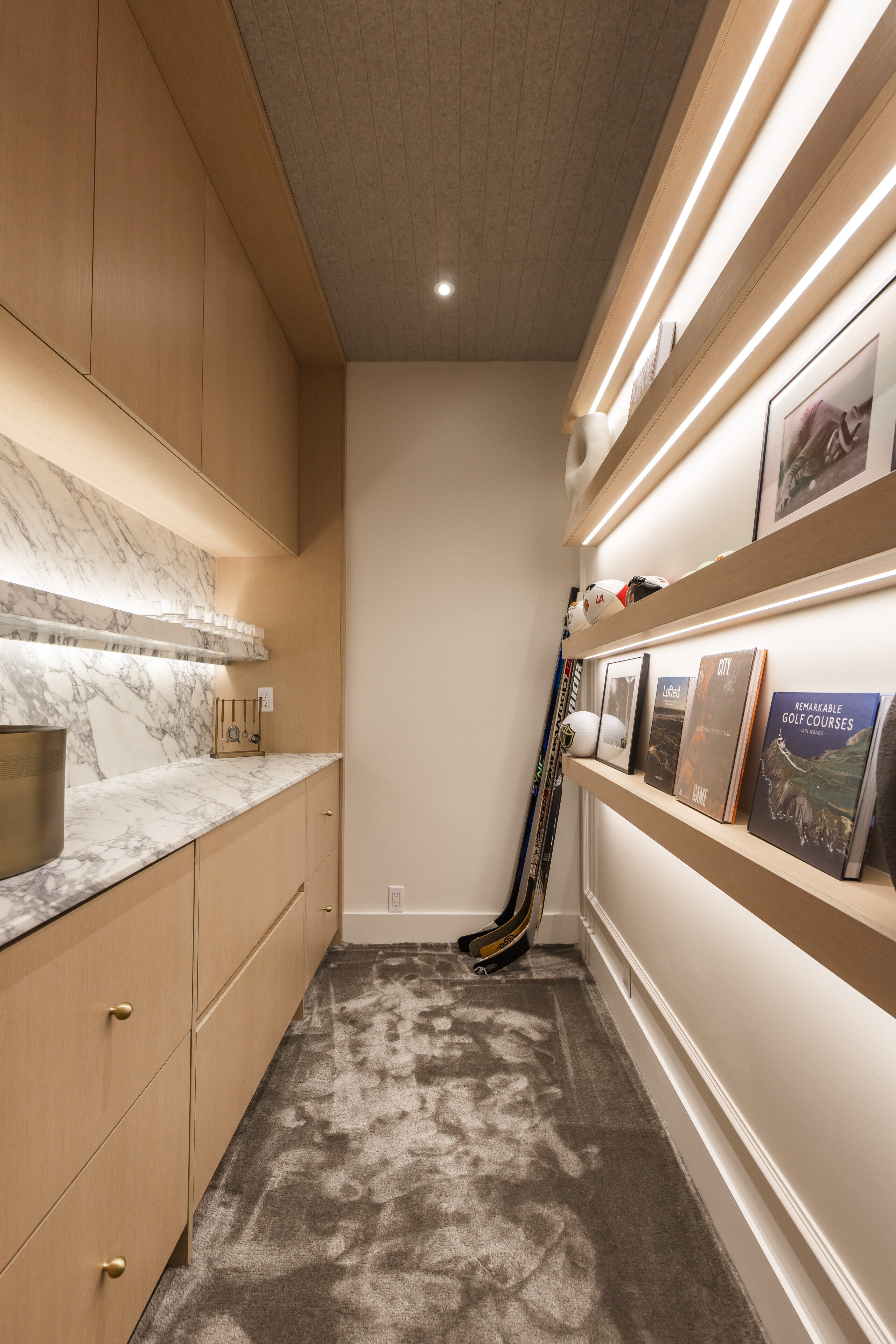 Elegant hallway featuring a marble countertop, stylish shelving, and a casual hockey stick for a blend of sophistication and personal charm.