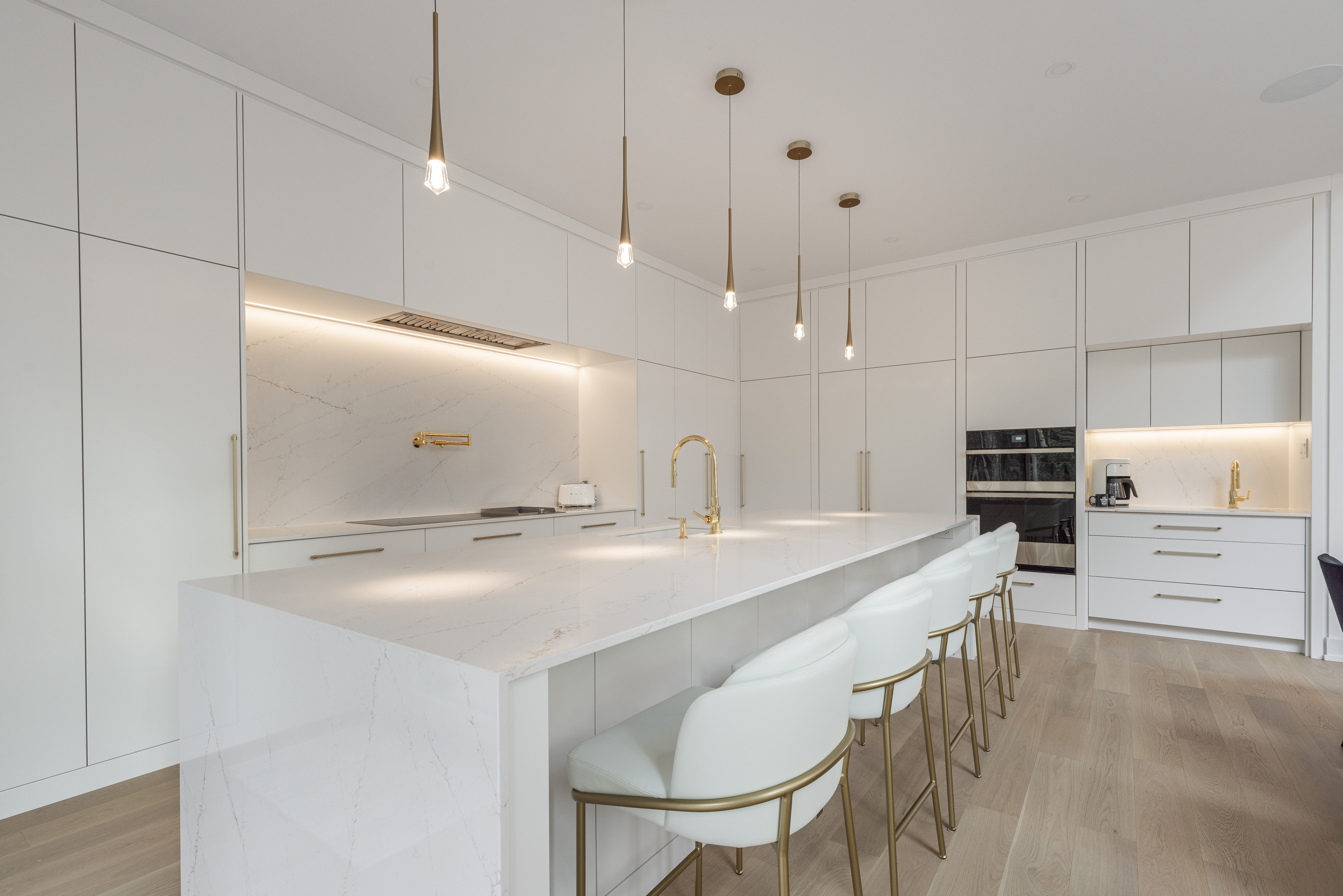 Experience the elegance of this modern kitchen with sleek cabinetry, a stunning marble island, and warm lighting for the perfect cooking atmosphere.