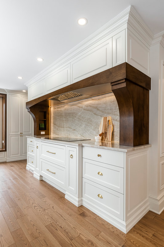Breathe elegance into your cooking with this stunning kitchen featuring white cabinetry, gold accents, and a unique natural stone backsplash.