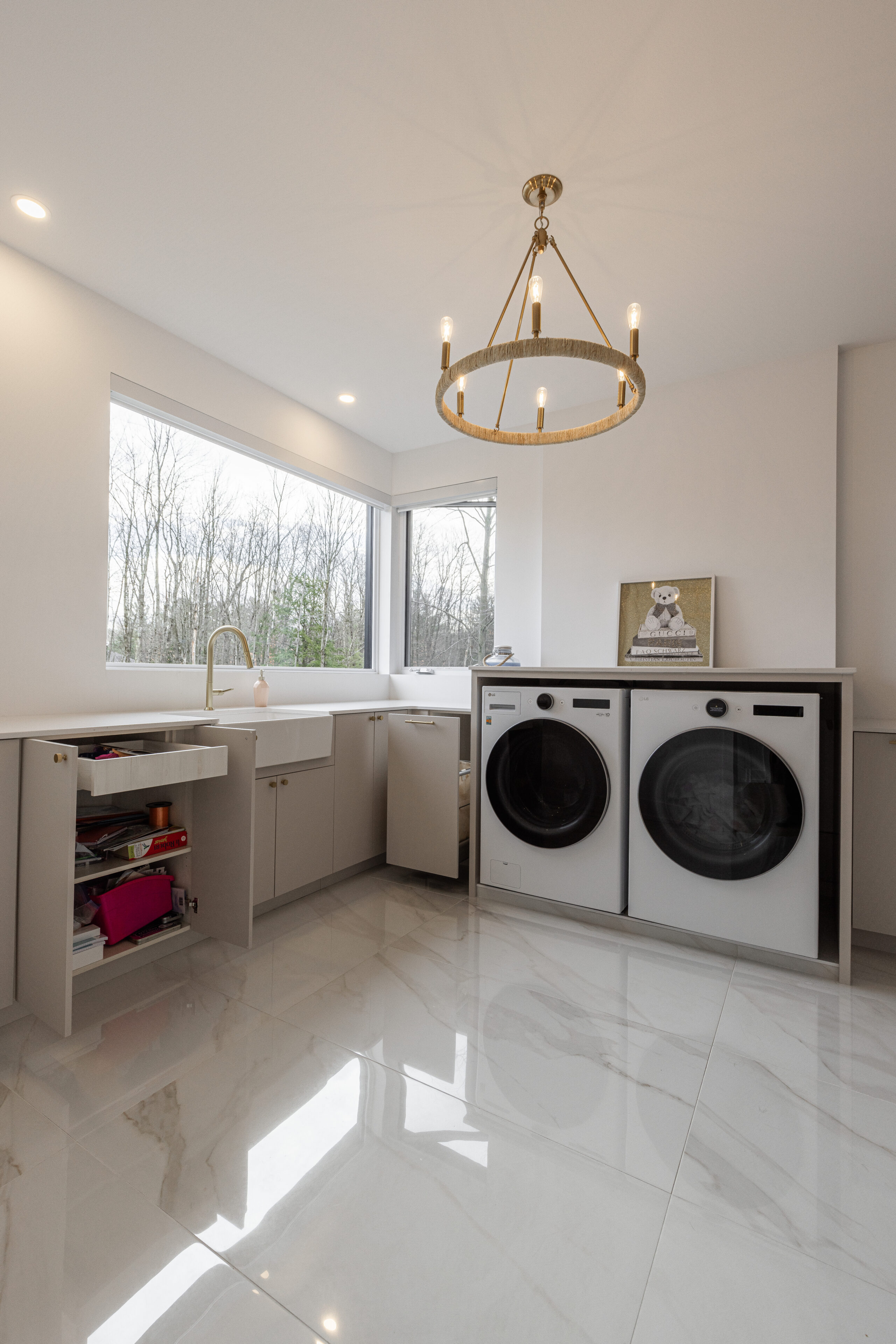 A bright and stylish laundry room featuring modern appliances, elegant lighting, and ample storage for a functional and inviting space.