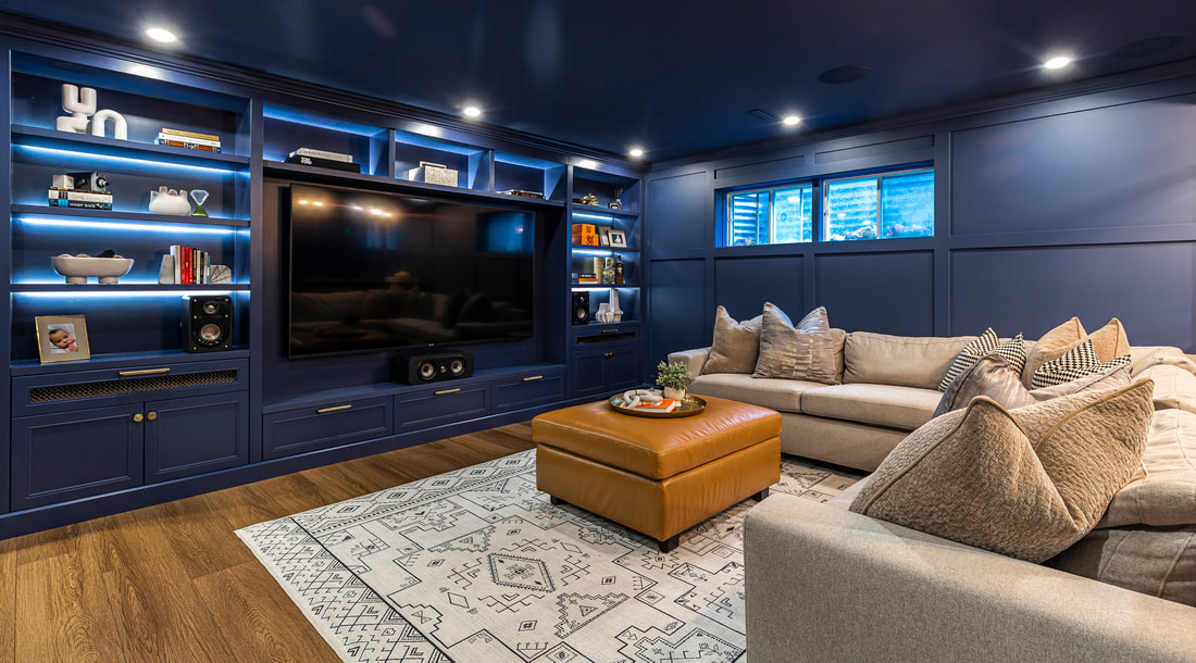 Experience modern comfort in this stylish media room featuring navy walls, plush seating, and custom shelving for an inviting atmosphere.
