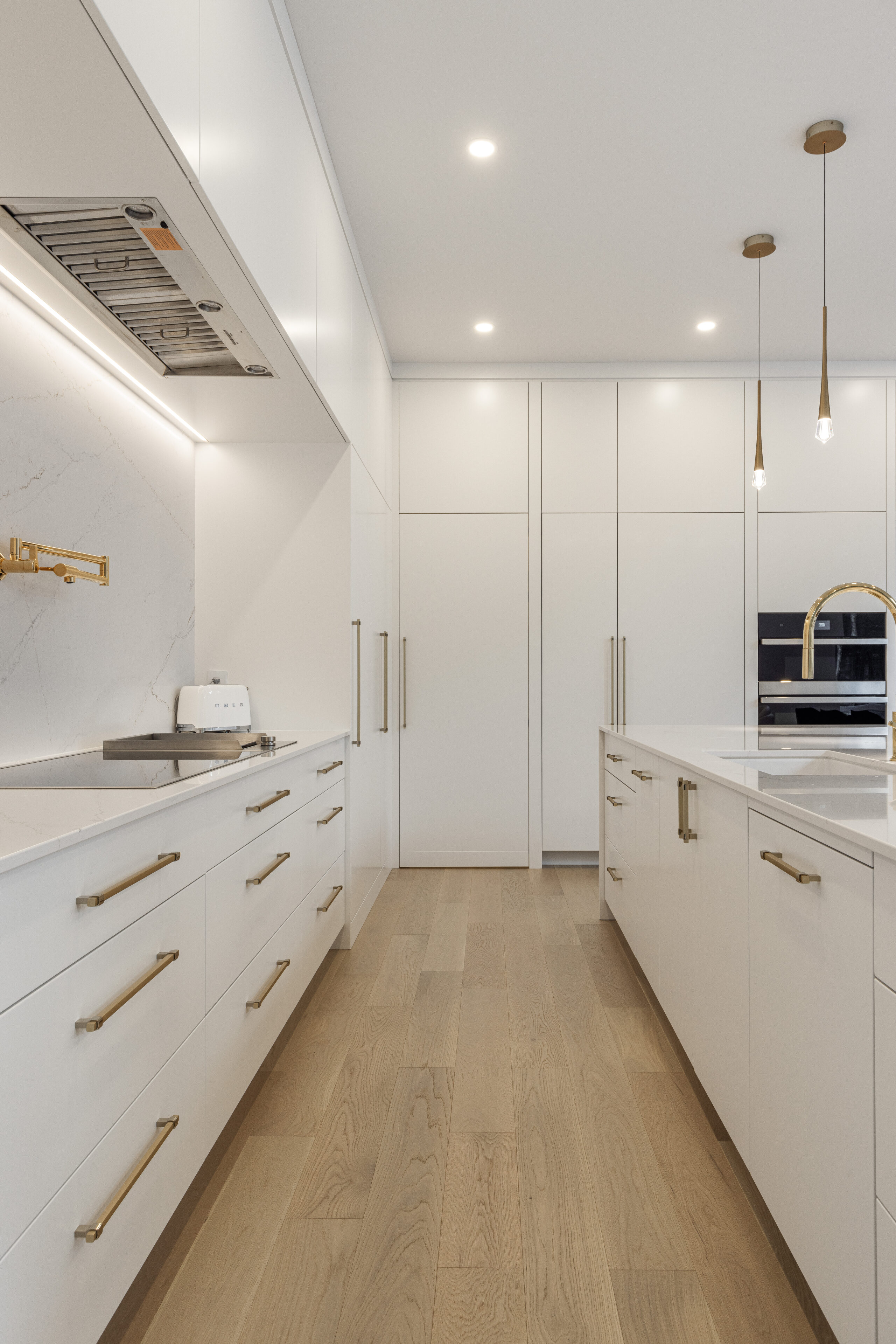 Sleek white cabinetry and gold accents define this inviting minimalist kitchen, perfect for culinary creativity and social gatherings.