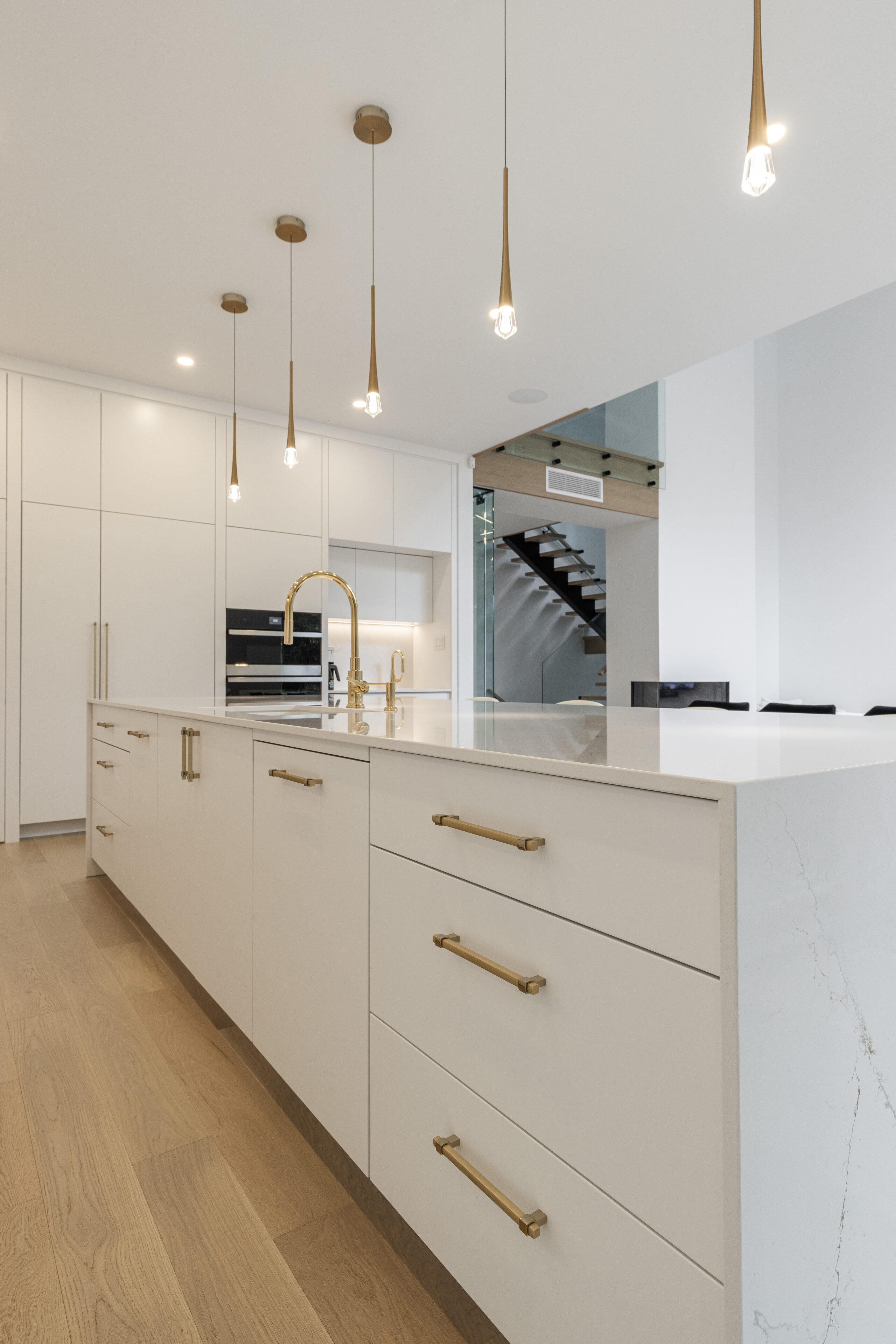 Modern minimalist kitchen featuring a spacious island, elegant lighting, and warm wooden accents for a stylish, functional space.