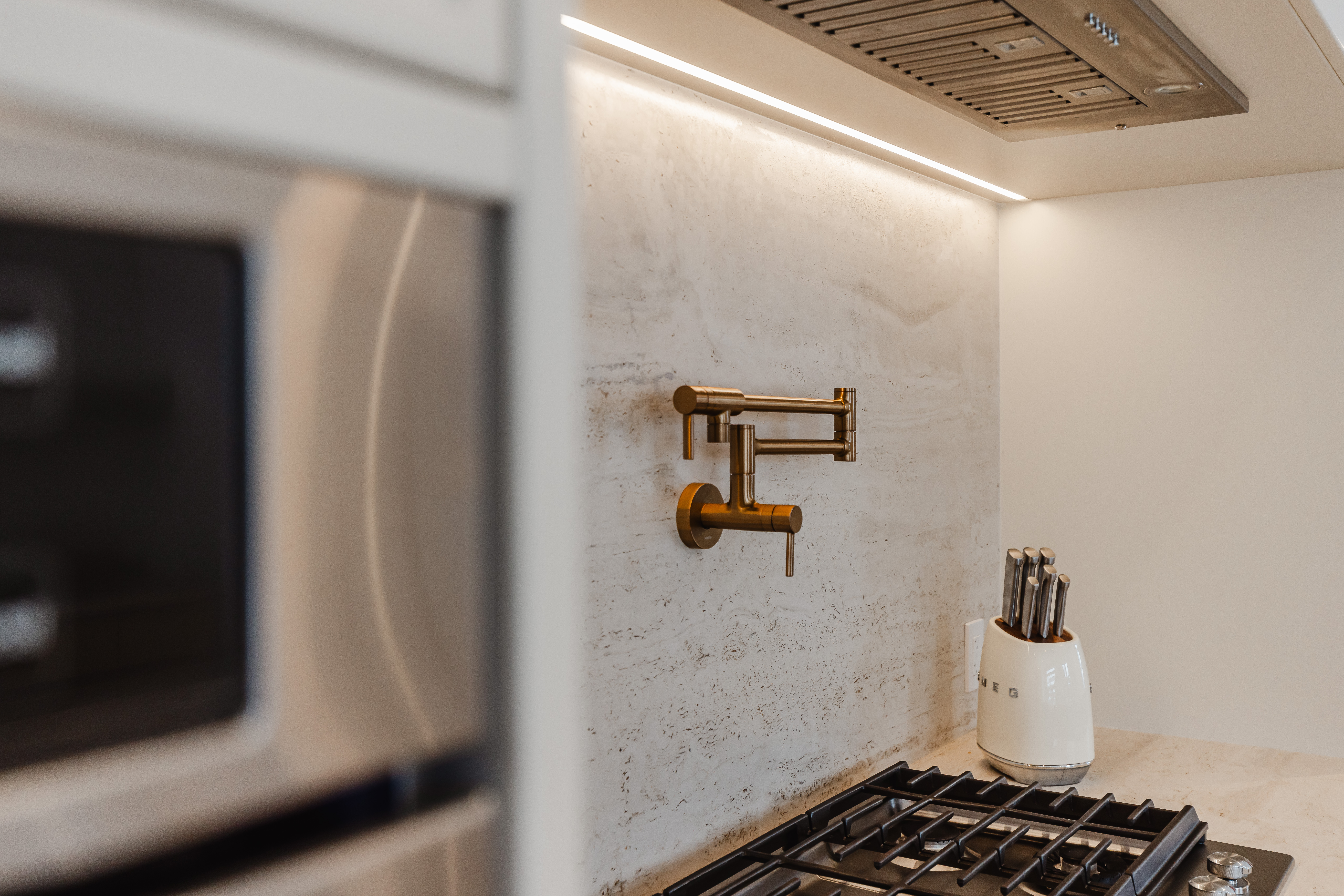 Discover a modern kitchen featuring a stunning brass faucet, sleek stainless steel appliances, and elegant ambient lighting.