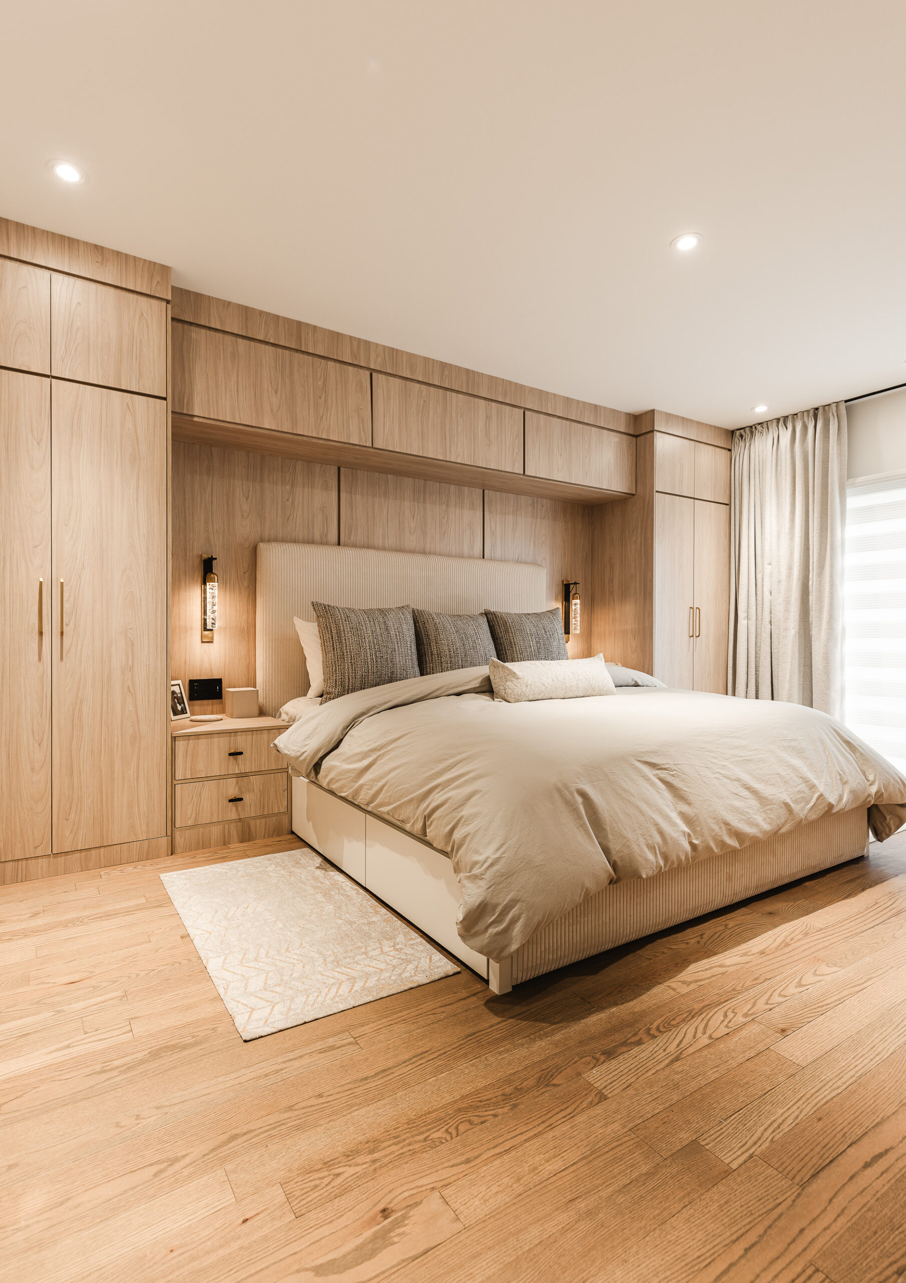 Experience tranquility in this modern bedroom, featuring a central bed, warm wood accents, and cozy ambient lighting for the perfect retreat.