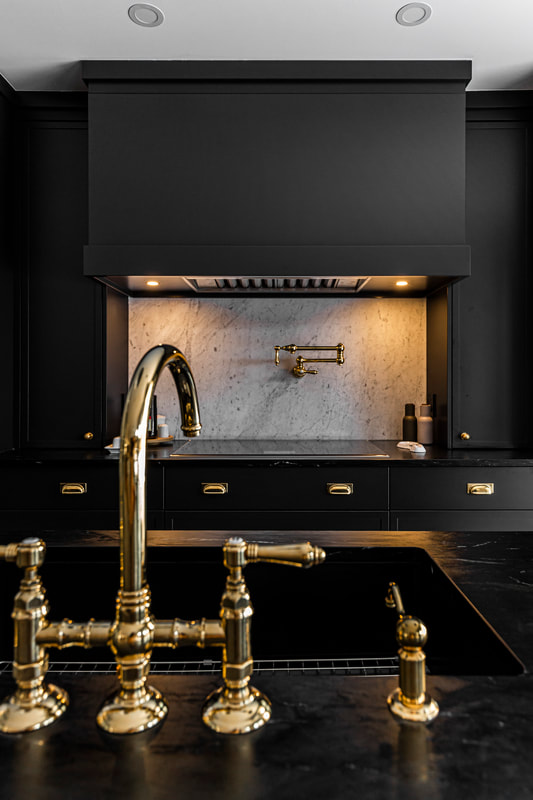 This modern kitchen features sleek black cabinetry and luxurious gold accents, blending elegance with timeless sophistication.