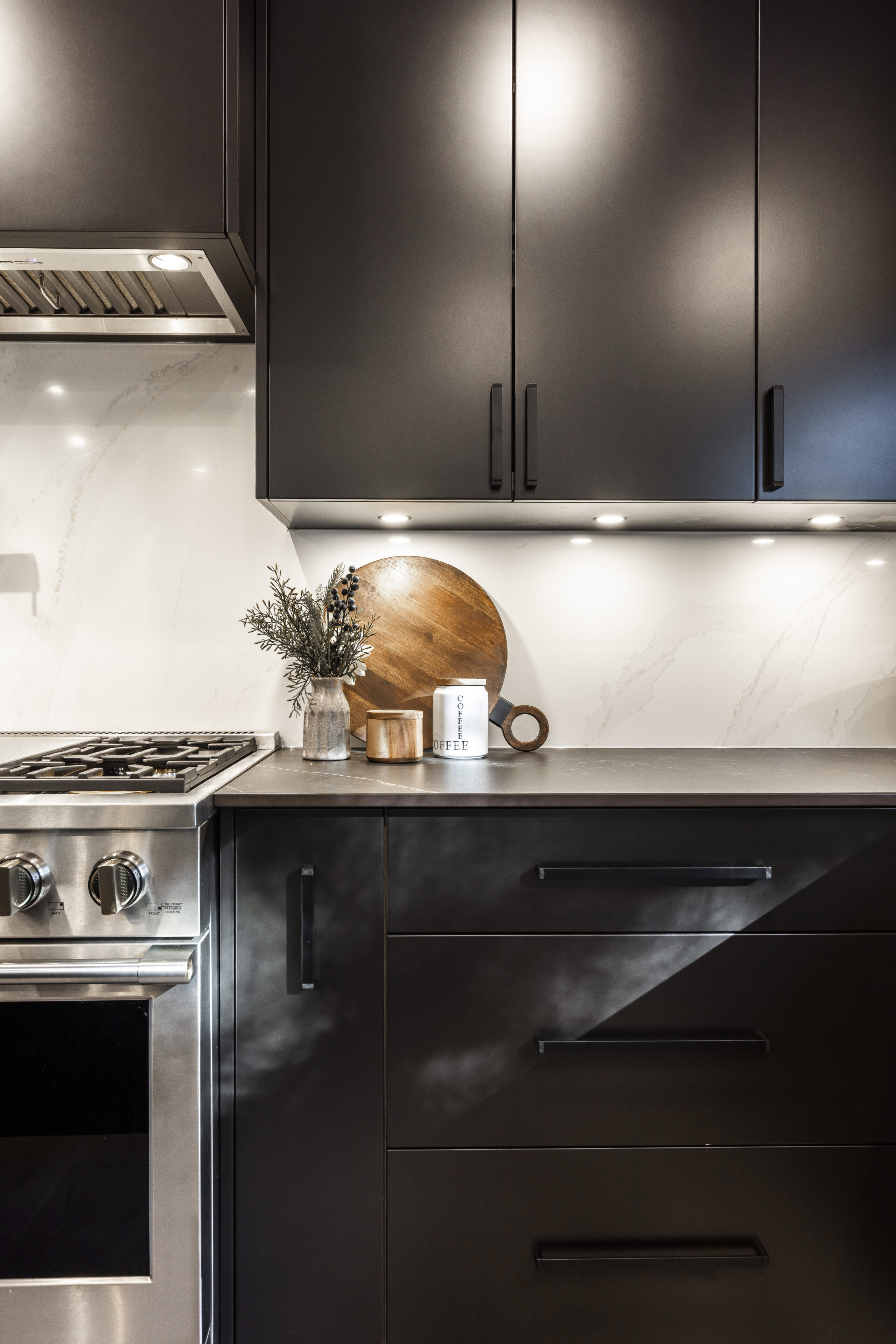 Experience the elegance of a modern black kitchen featuring sleek cabinetry, stainless steel appliances, and warm decorative accents.