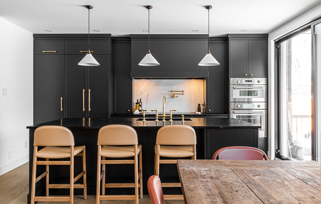 Stylish black kitchen blends sophistication with a rustic dining table, creating a warm, inviting space for family gatherings.