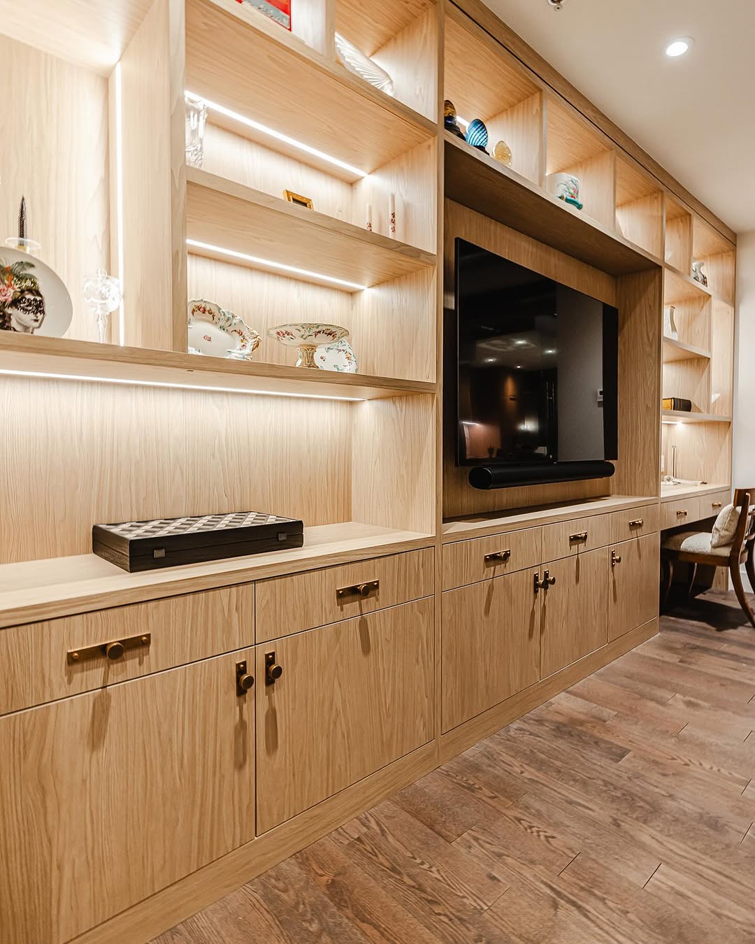 A chic modern entertainment unit features a wall-mounted TV, illuminated shelves, and a sleek storage cabinet for a cozy and stylish home ambiance.