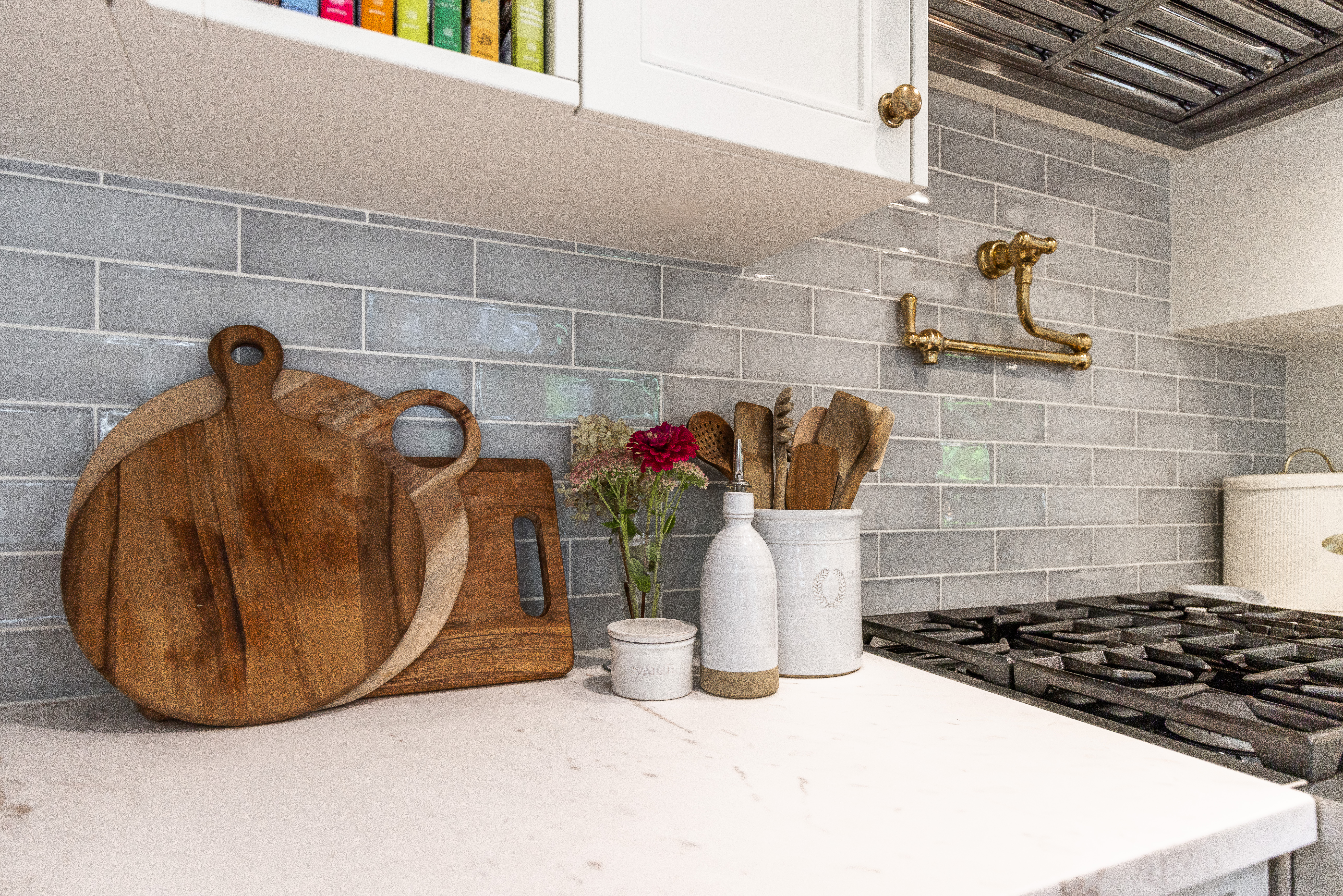 A modern kitchen features elegant stone countertops, wooden cutting boards, rustic utensils, and a vibrant floral arrangement for a welcoming touch.