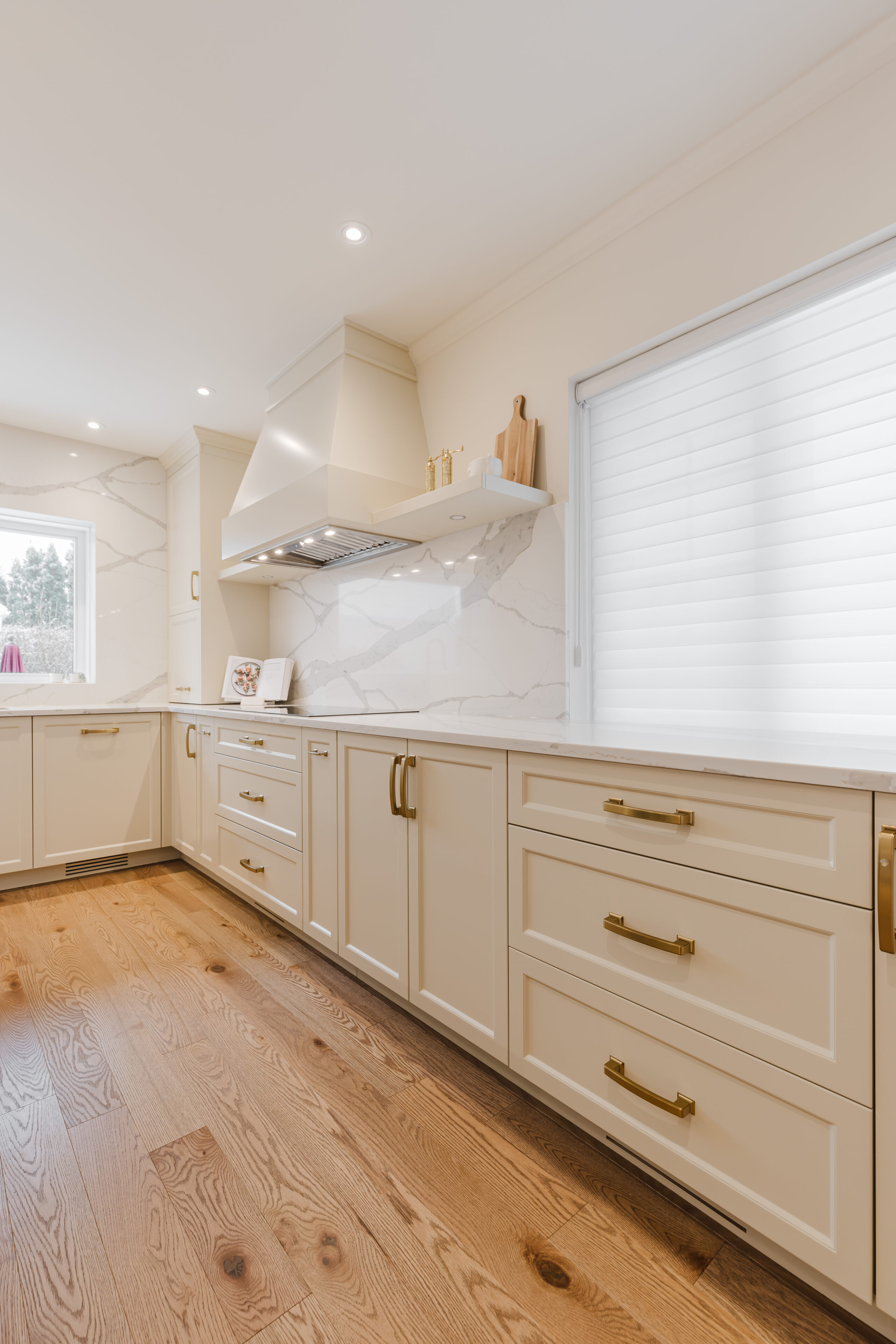 Bright and inviting modern kitchen featuring cream cabinetry, gold accents, and natural light for a stylish cooking space.