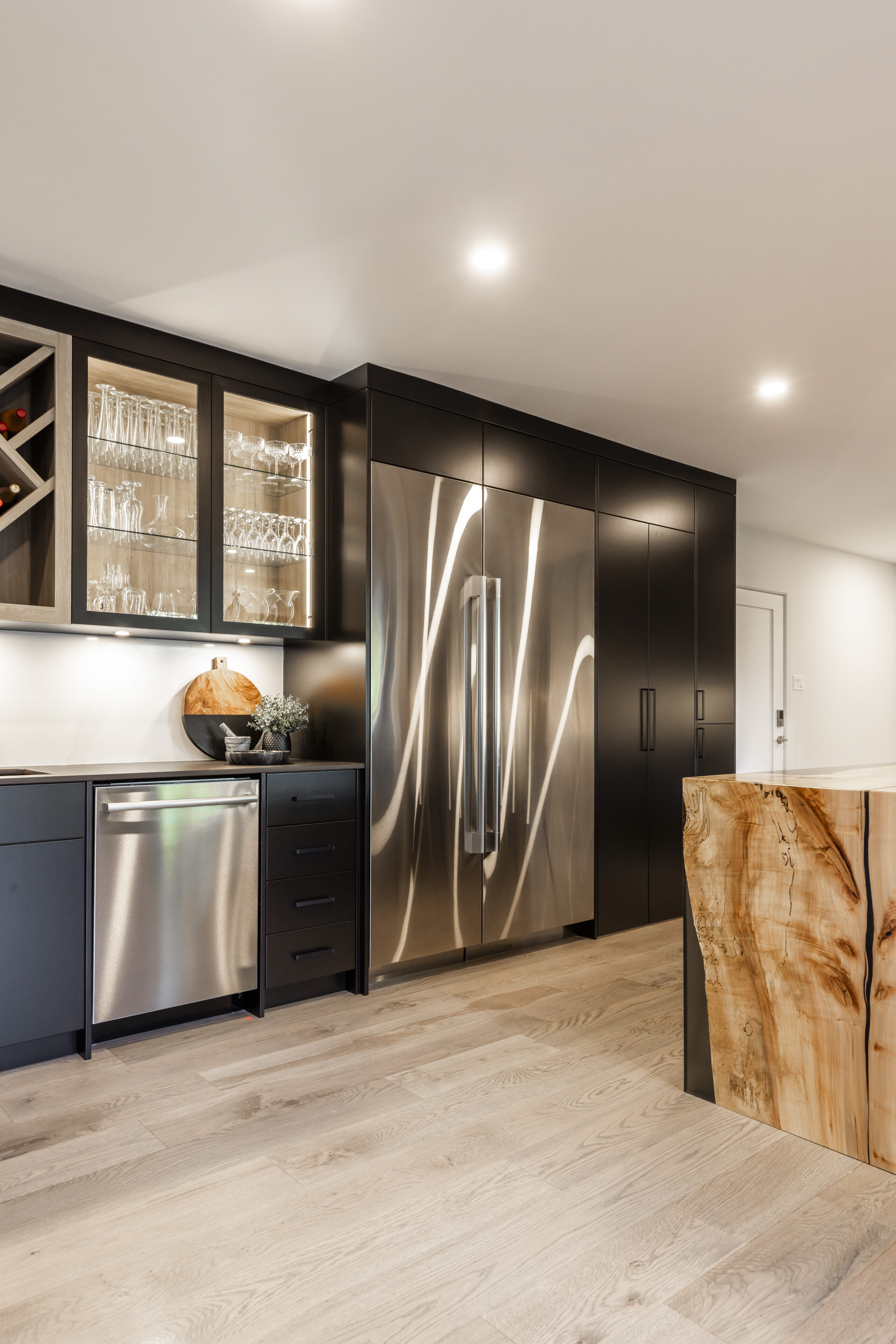 Discover a modern kitchen that features sleek dark cabinetry, a rustic wooden island, and stylish stainless steel appliances for a welcoming culinary space.
