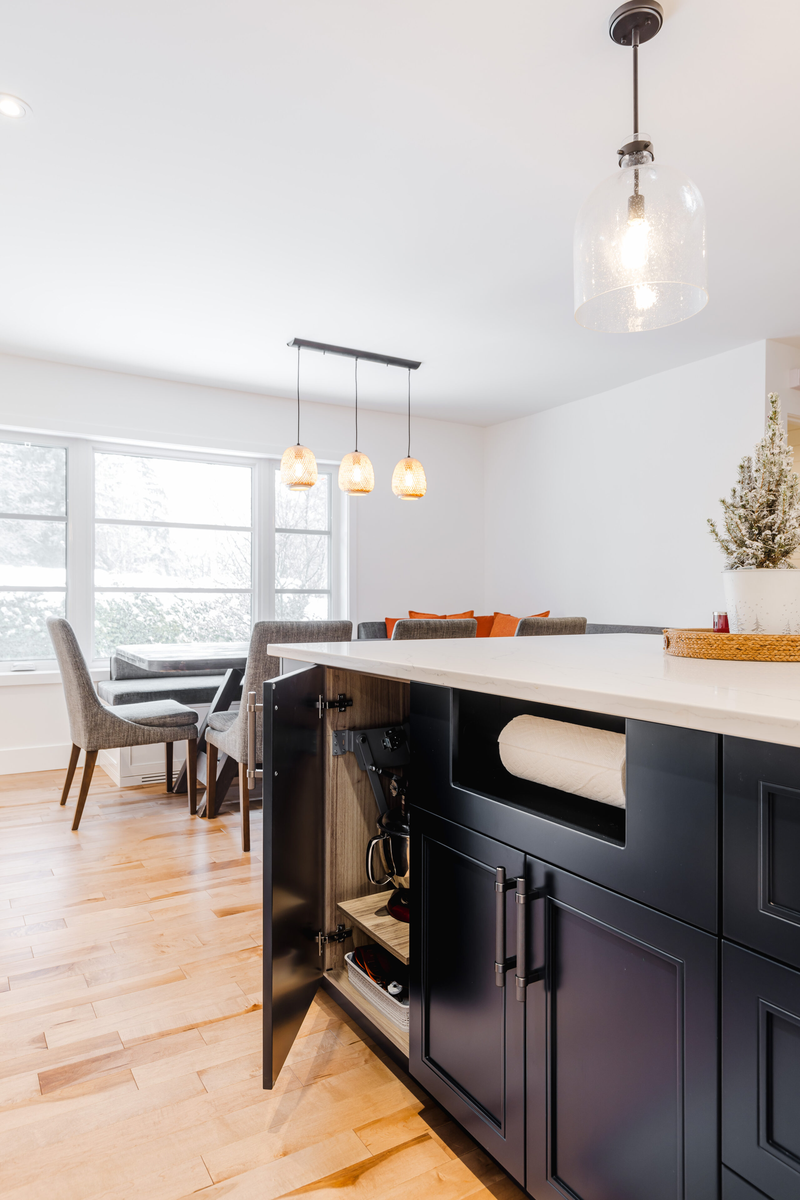 Bright and modern open-concept kitchen with a dark island, cozy dining area, and abundant natural light for a welcoming atmosphere.