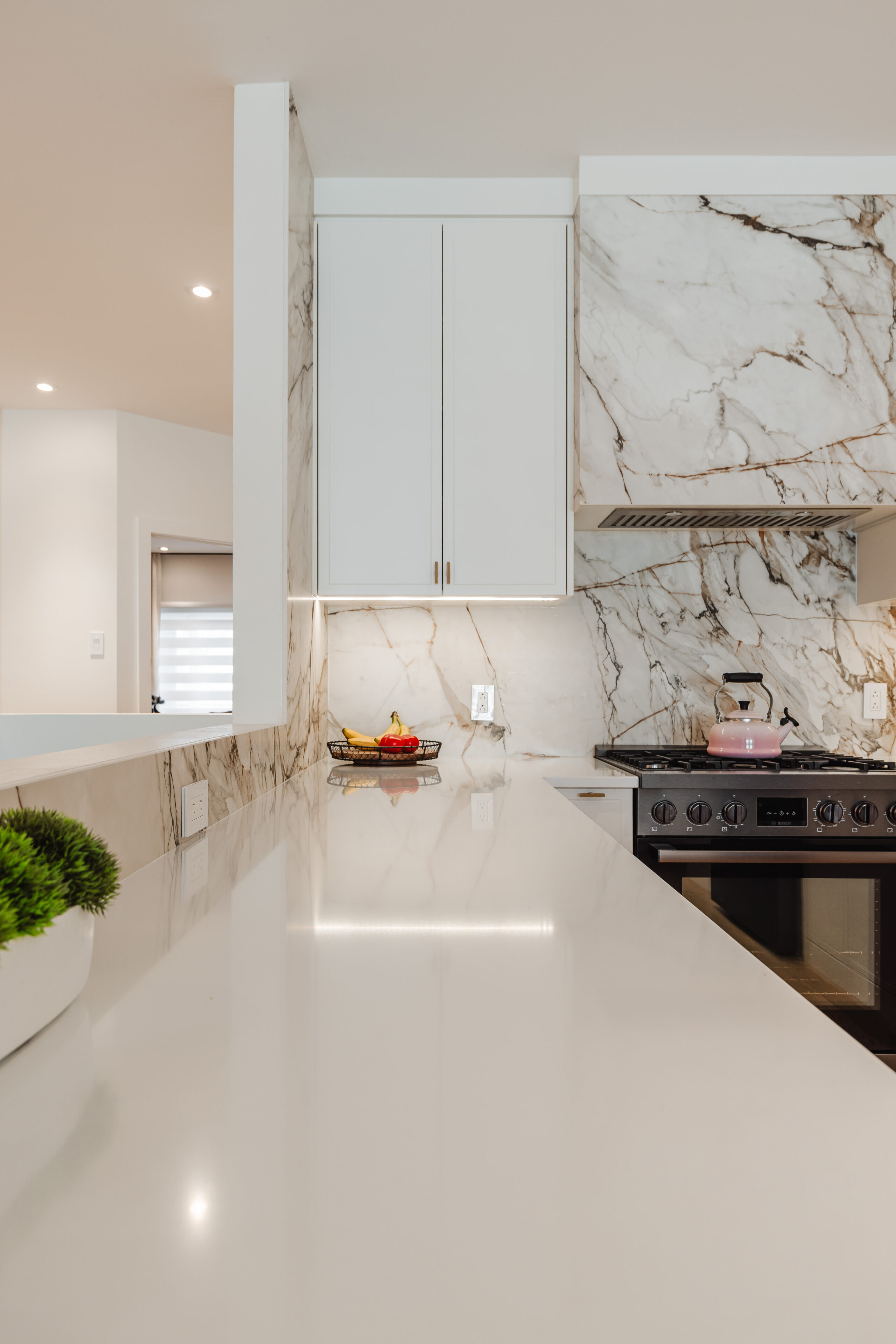 Discover a stunning modern kitchen featuring a glossy countertop, sleek white cabinetry, and a dramatic marble backsplash, perfect for cooking and entertaining.