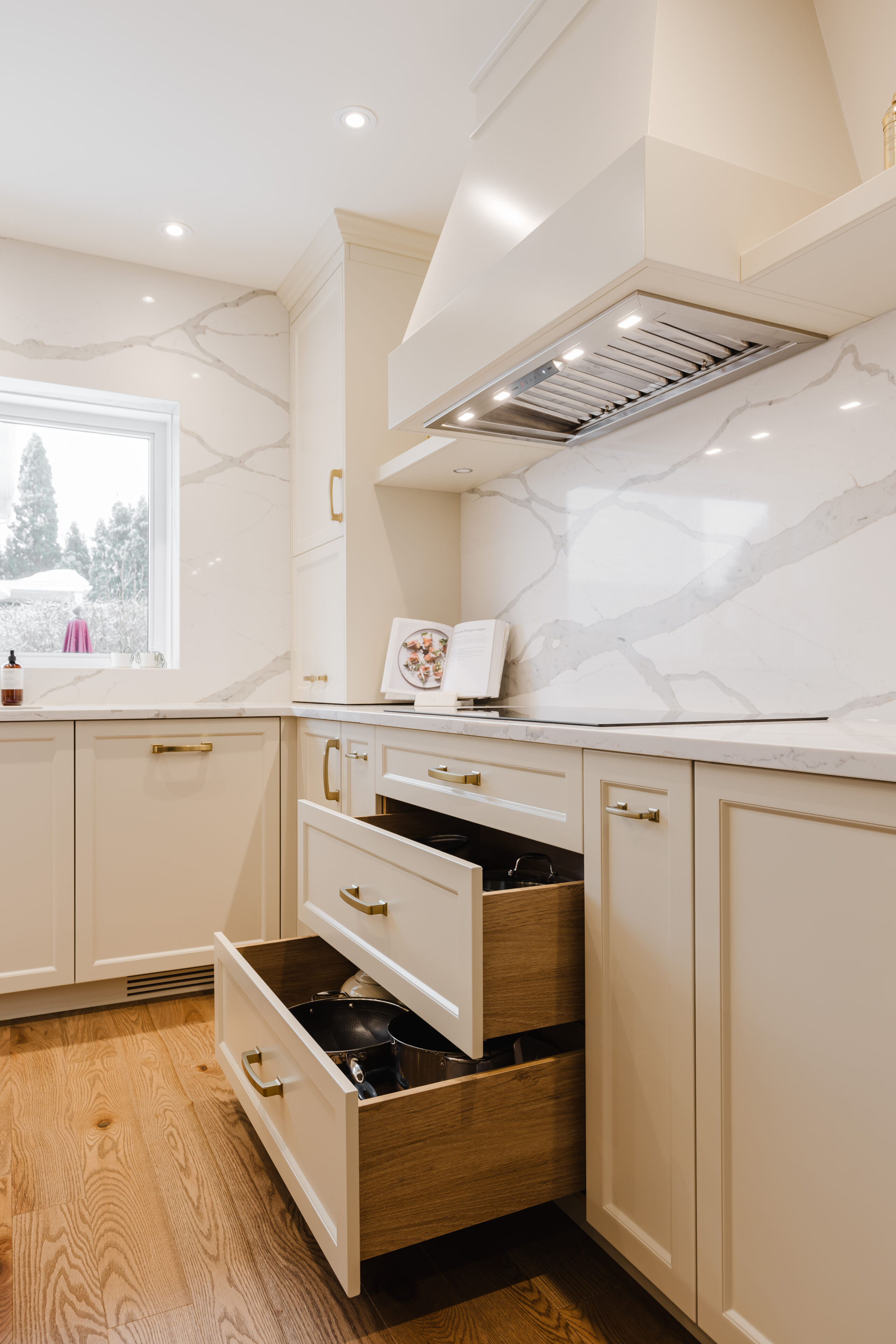 This modern kitchen features cream cabinetry, natural wood floors, and ample natural light for a stylish and functional culinary space.