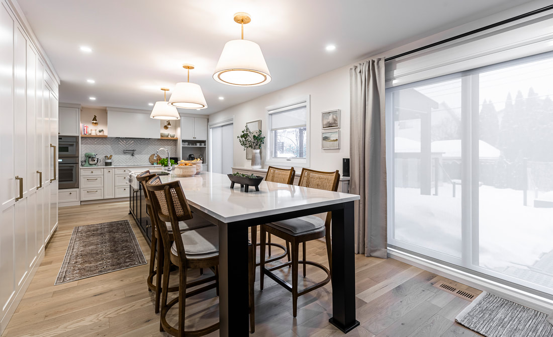 A modern kitchen features a cozy dining area with elegant lighting and snowy views, perfect for meals and entertaining.