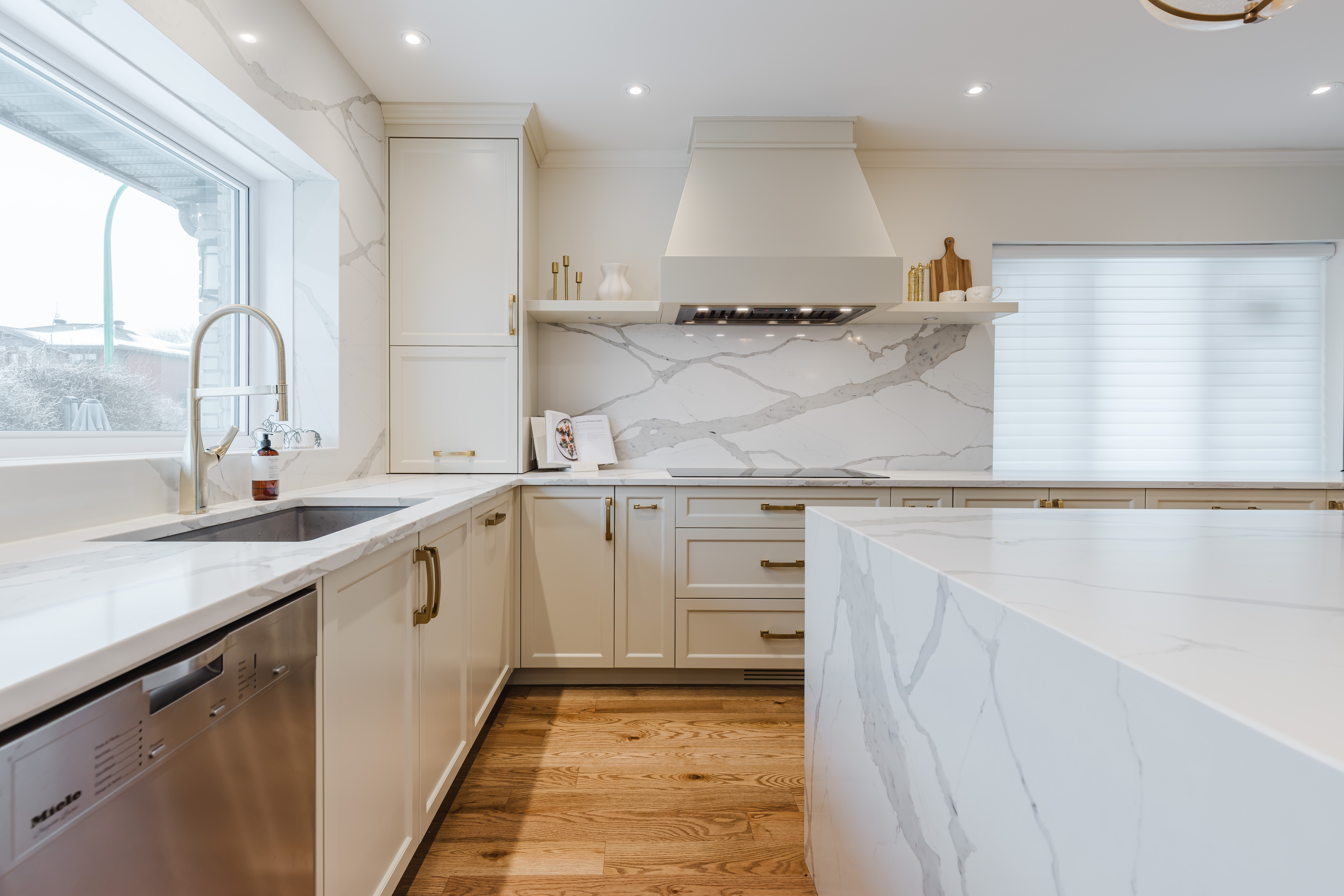 Discover a bright modern kitchen featuring white cabinetry, a stunning marble island, and elegant gold accents for a sophisticated touch.