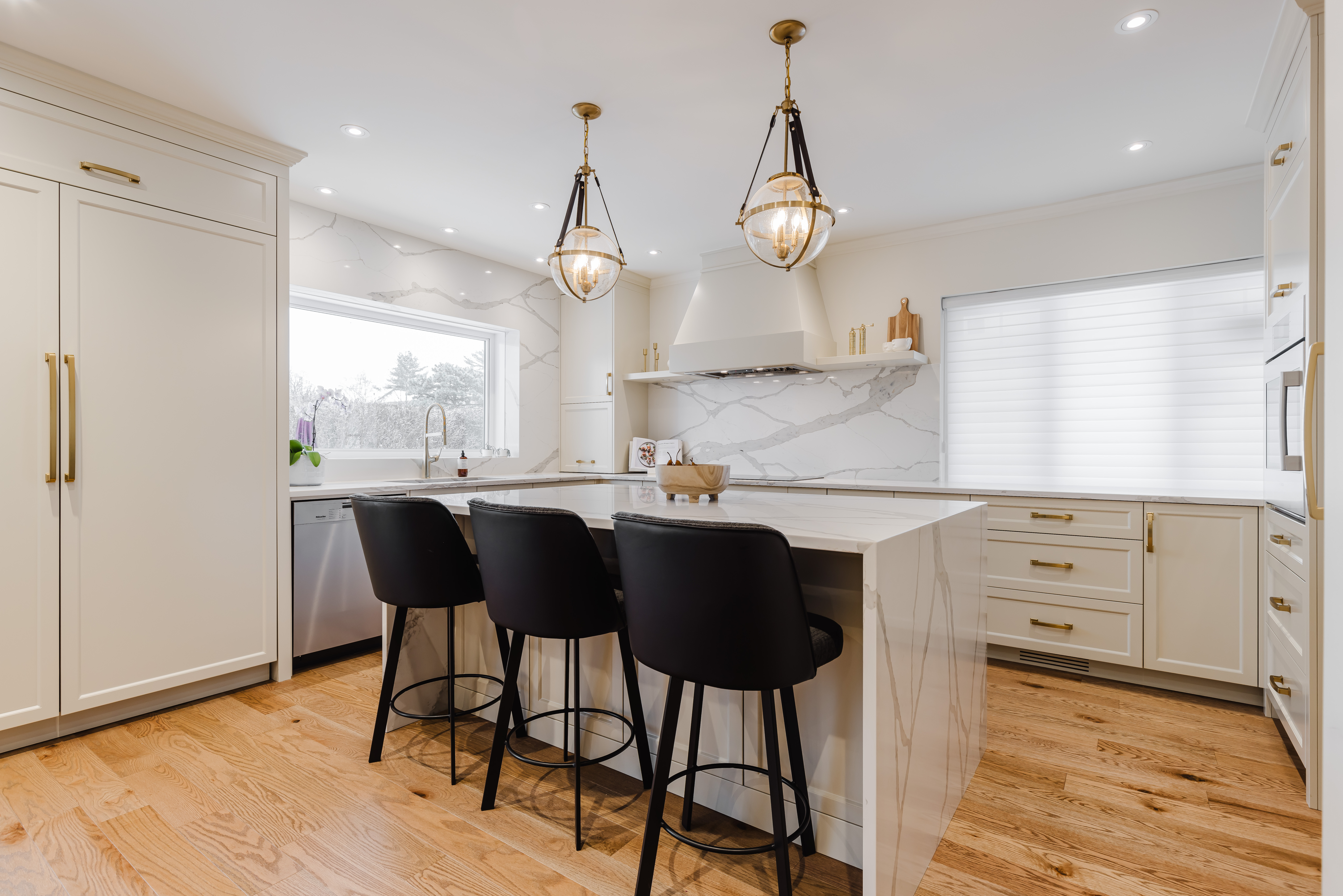 Bright and elegant modern kitchen featuring a luxurious marble island, sleek white cabinetry, and inviting natural light.