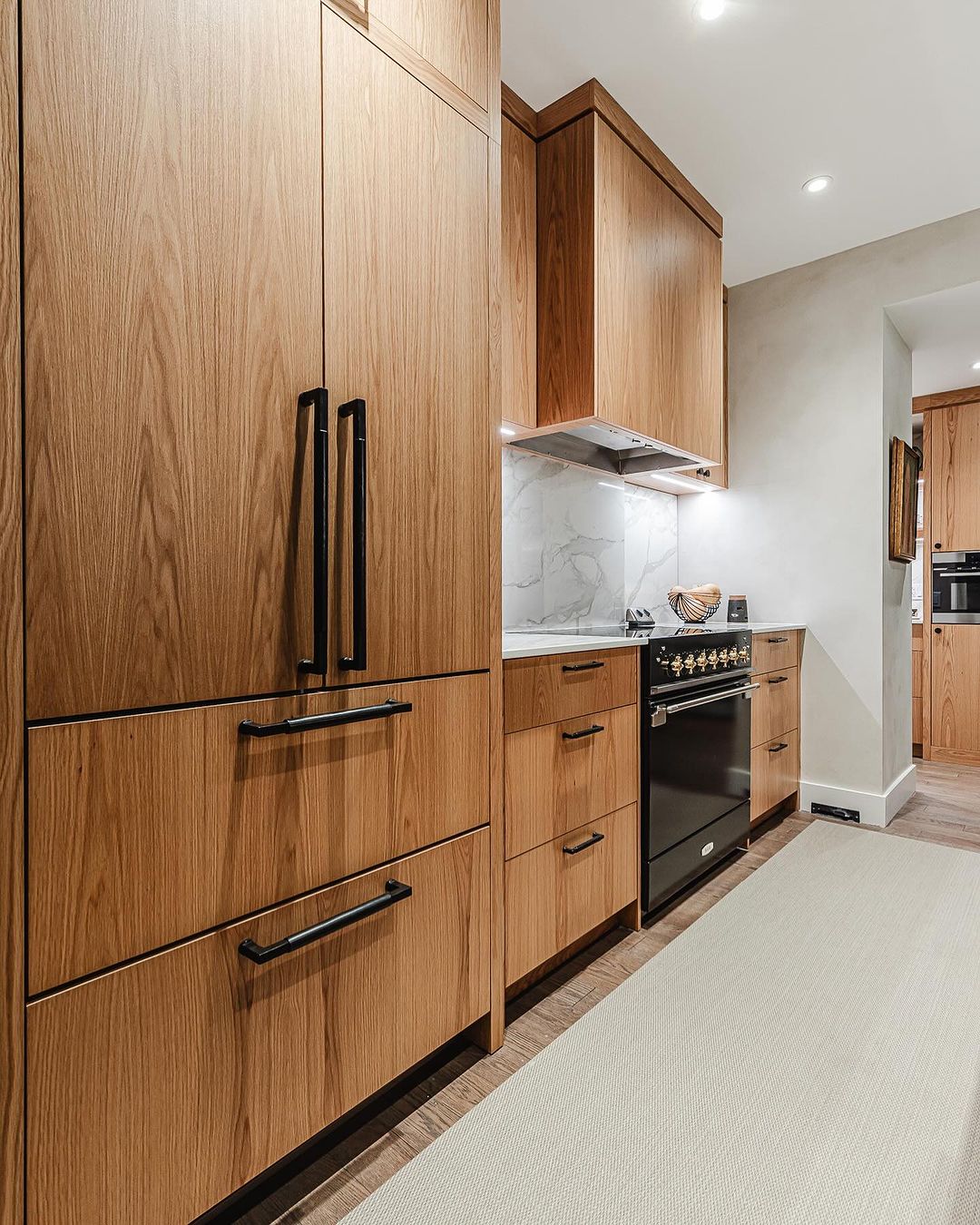 Discover a stylish modern kitchen featuring warm wood cabinetry, a sleek stainless steel range, and elegant marble accents.