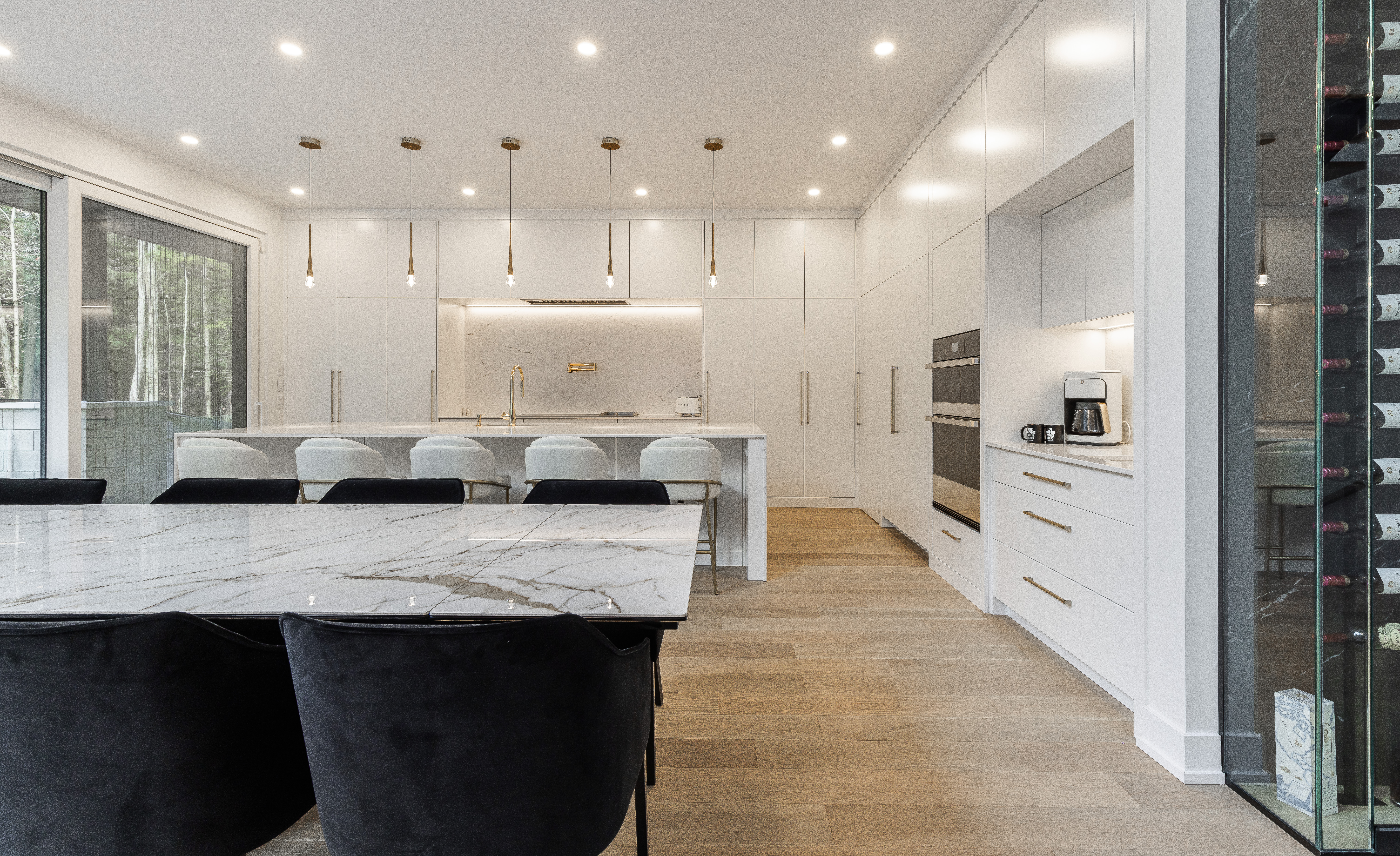 A stunning modern kitchen featuring a marble island, sleek cabinetry, and abundant natural light creating an inviting dining space.