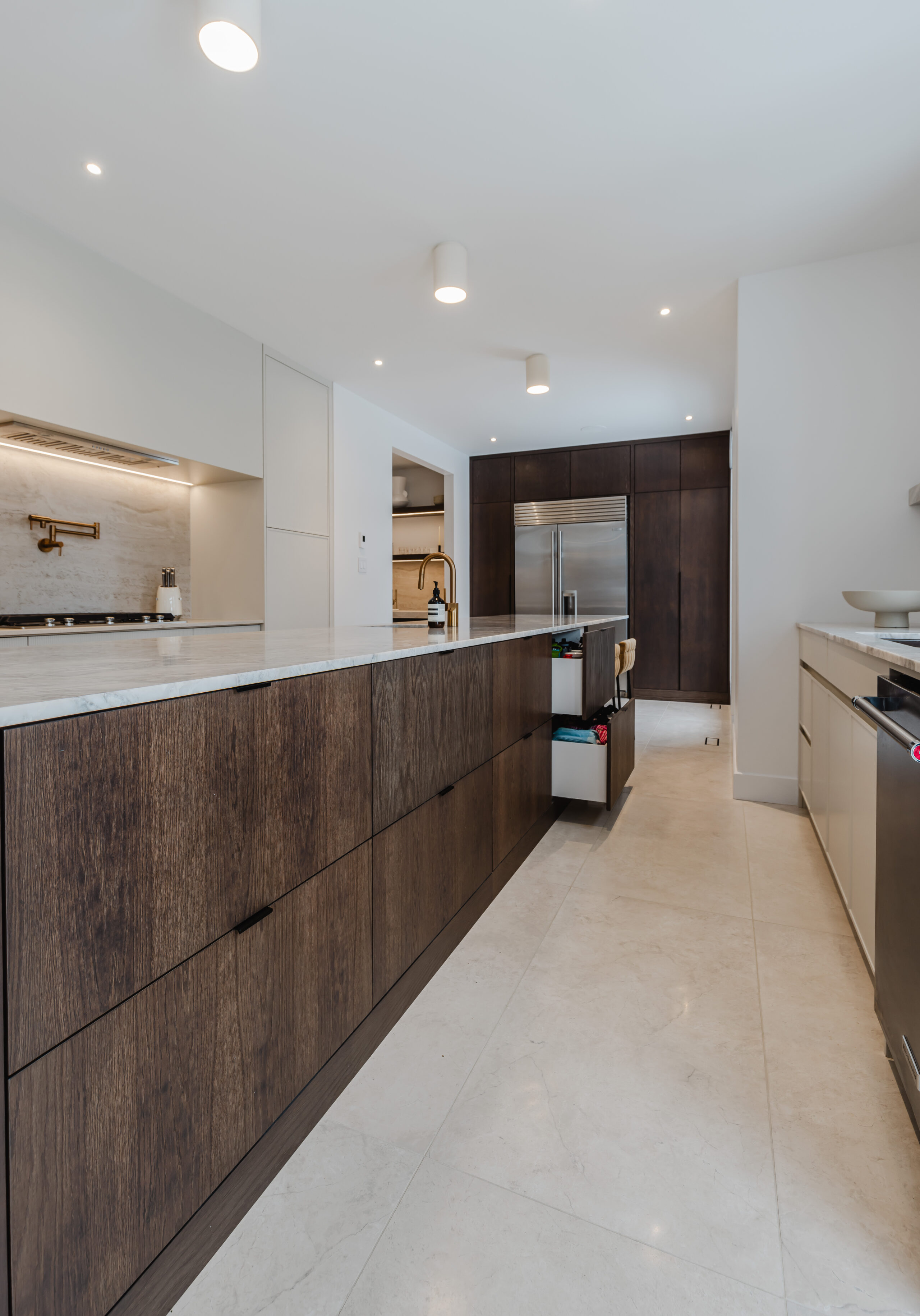 Discover a modern minimalist kitchen with a dark wood island, sleek stainless steel appliances, and bright white cabinetry for a stylish cooking space.