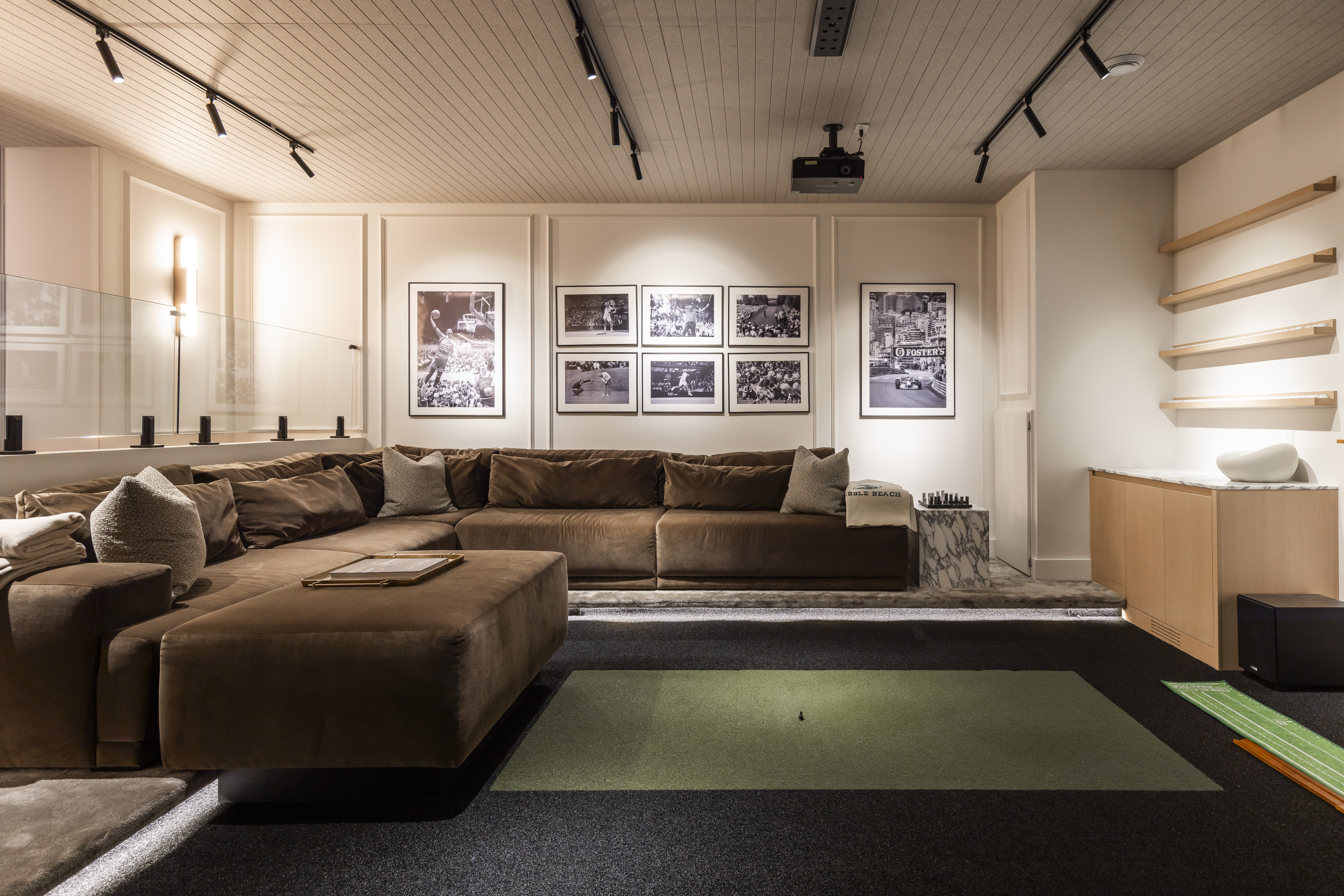 A cozy modern living room features a plush sectional sofa, vibrant green carpet, and artistic black-and-white photography for a stylish ambiance.