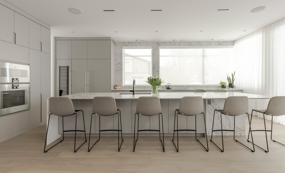 Discover a sleek, modern kitchen with white cabinetry, a marble island, and airy natural light, perfect for style and casual entertaining.