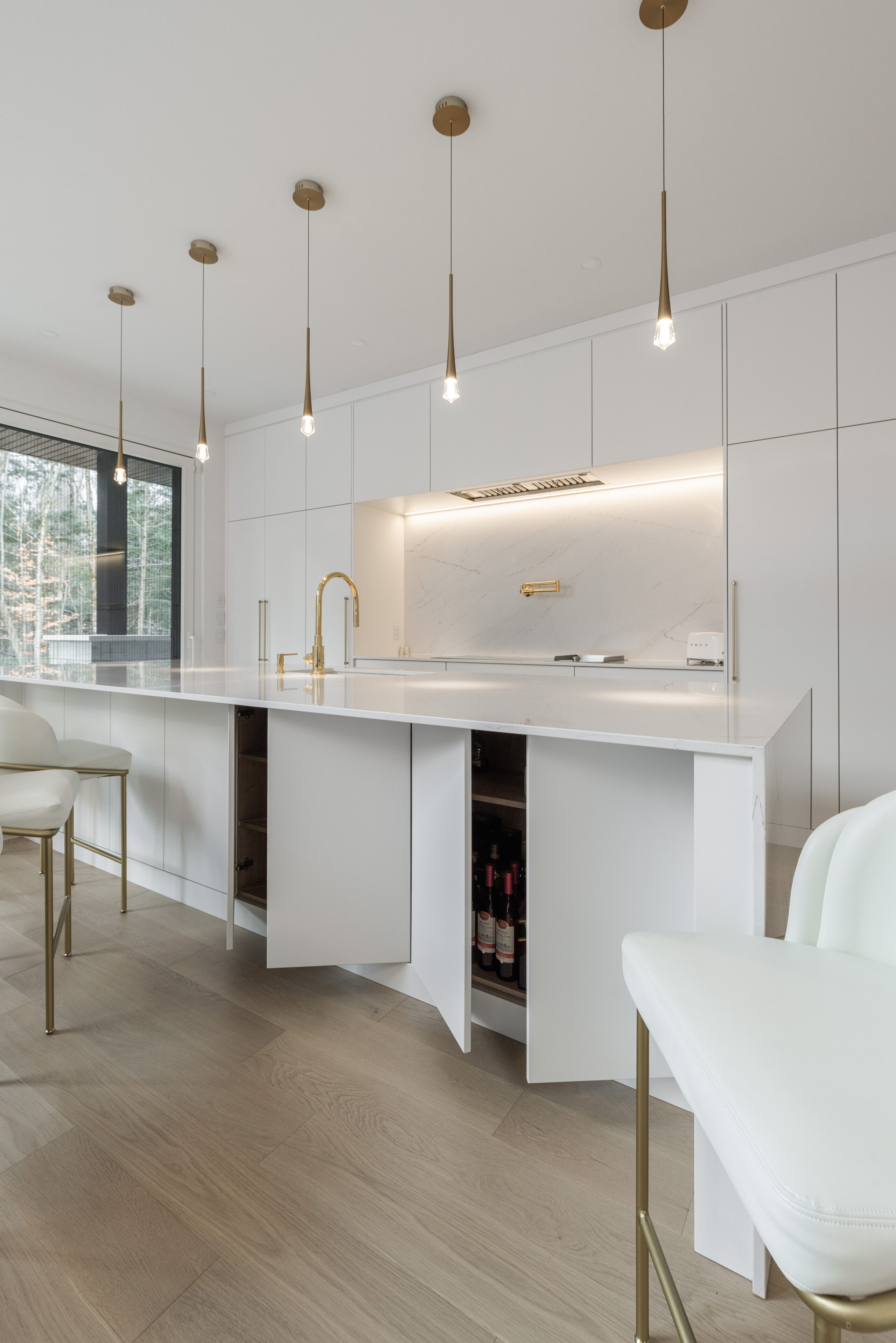 Discover a sleek, modern kitchen with elegant white cabinetry and gold accents, perfect for entertaining and enjoying natural light.