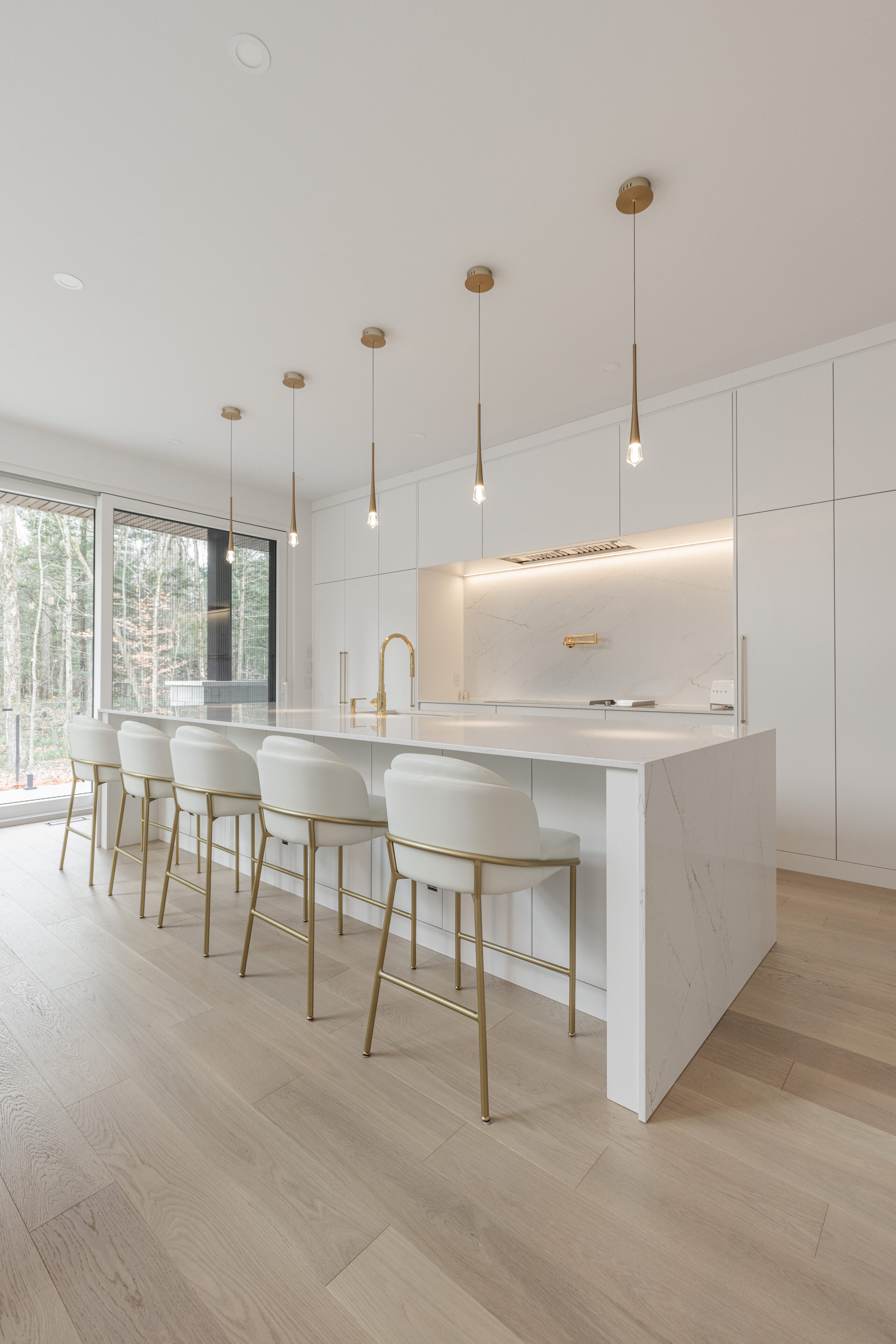 Stylish modern kitchen in Quebec featuring sleek white cabinetry, a spacious island, and abundant natural light for a warm, inviting atmosphere.