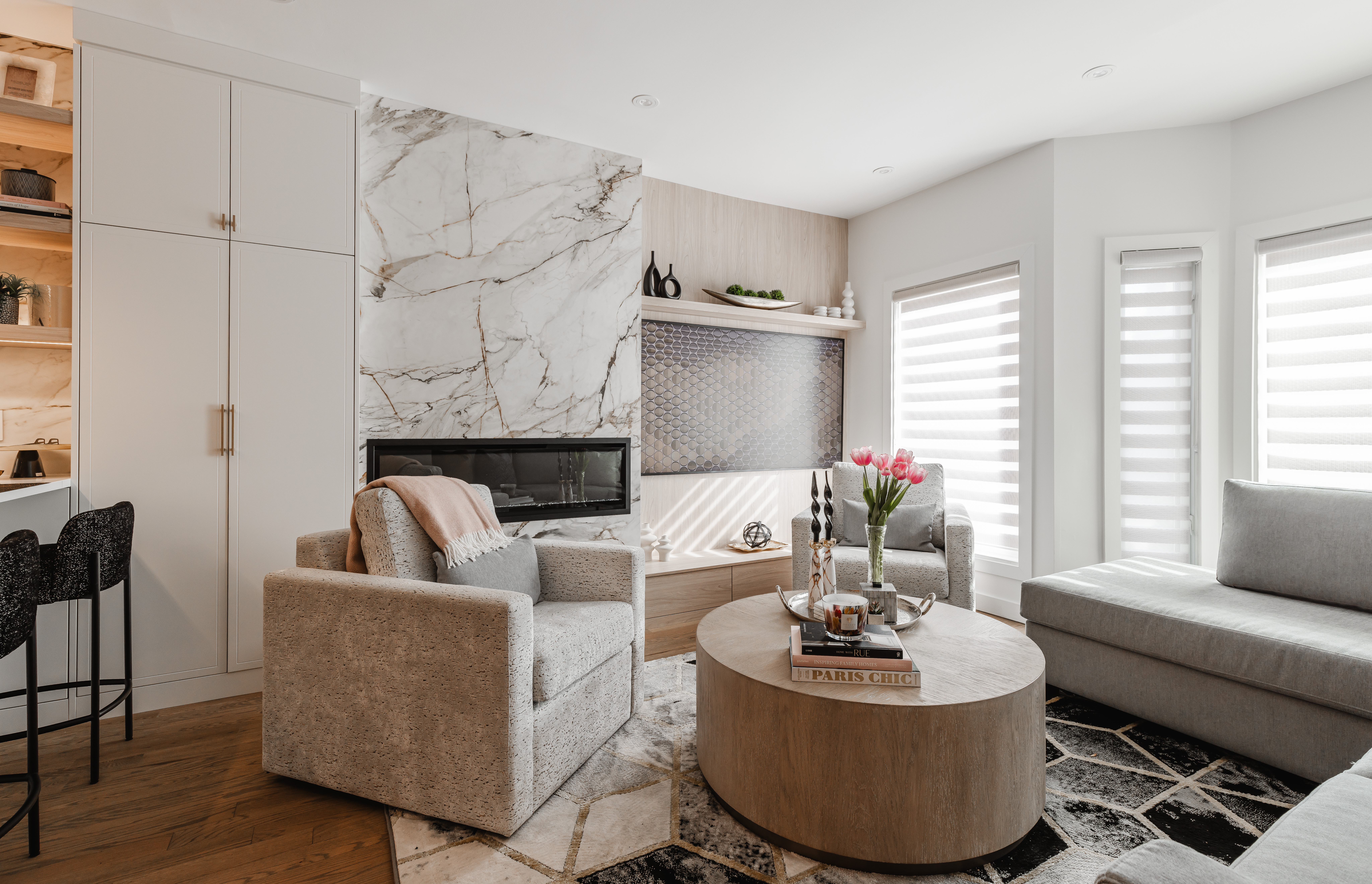 Discover a chic modern living room featuring a stylish marble fireplace, cozy seating, and abundant natural light for an inviting atmosphere.