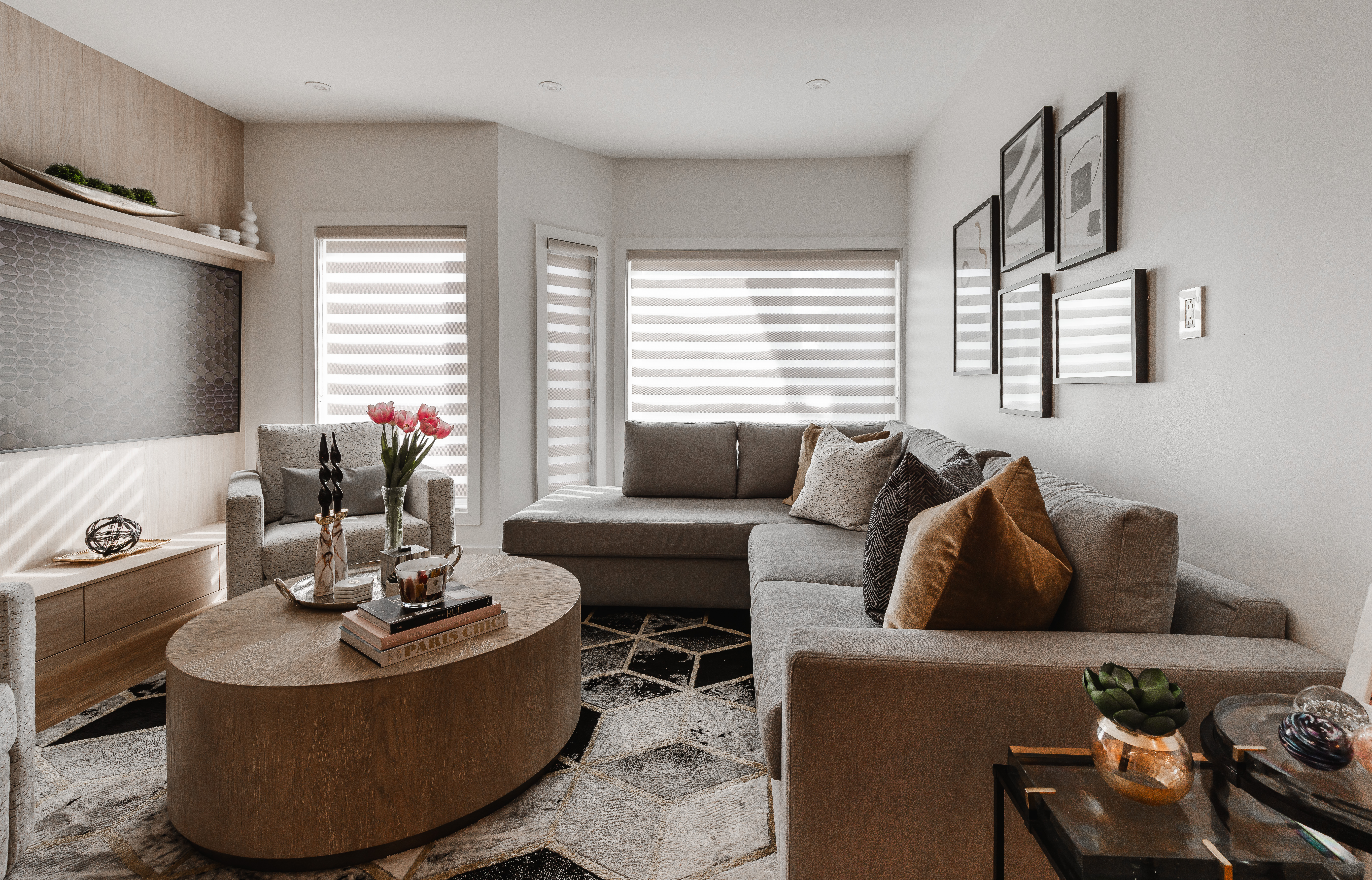 Bright and airy modern minimalist living room featuring a light gray sectional, geometric rug, and a charming wooden coffee table with fresh flowers.