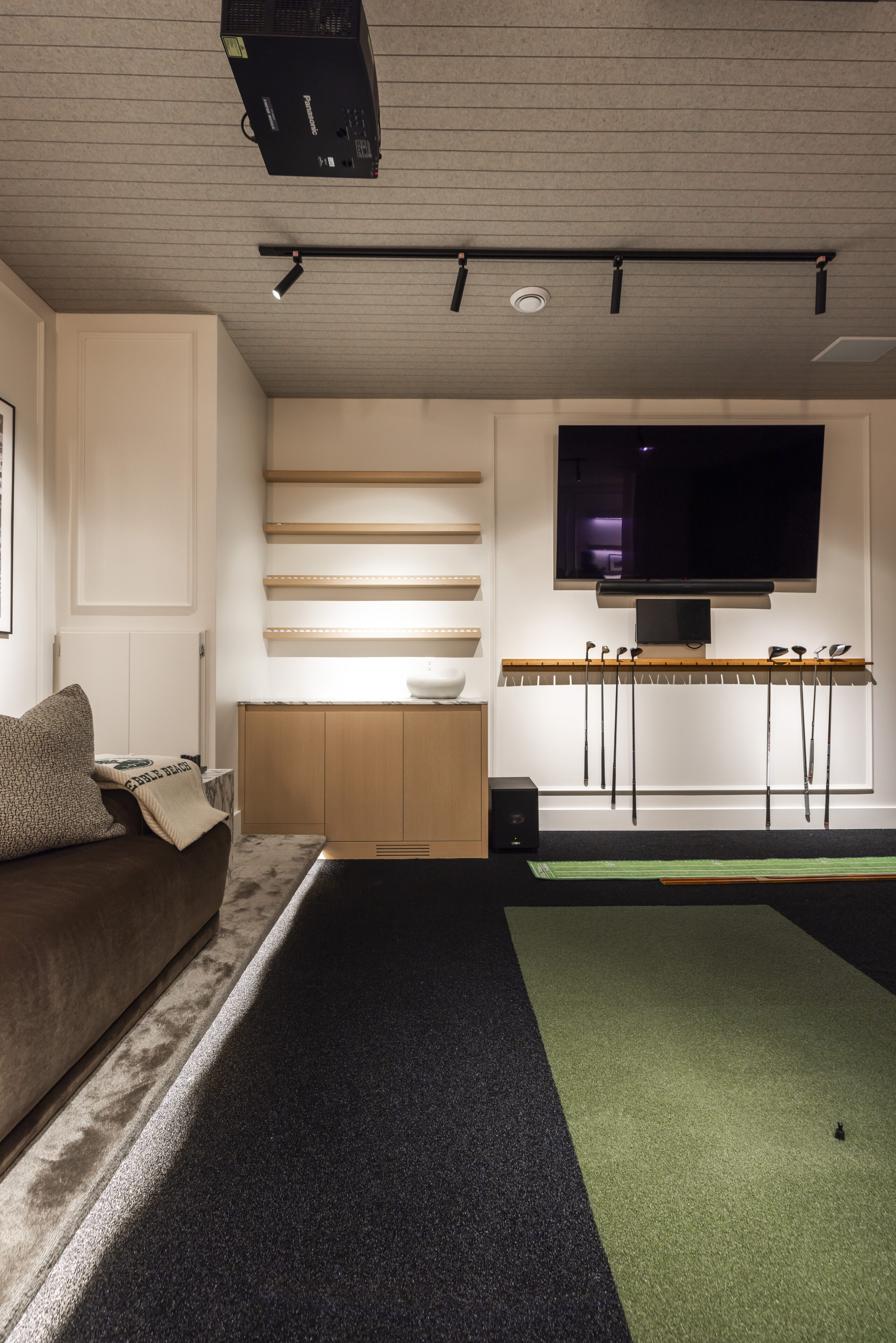 Stylish modern living room with a plush sofa, sleek TV, and inviting green carpets offers the perfect setting for relaxation and entertainment.