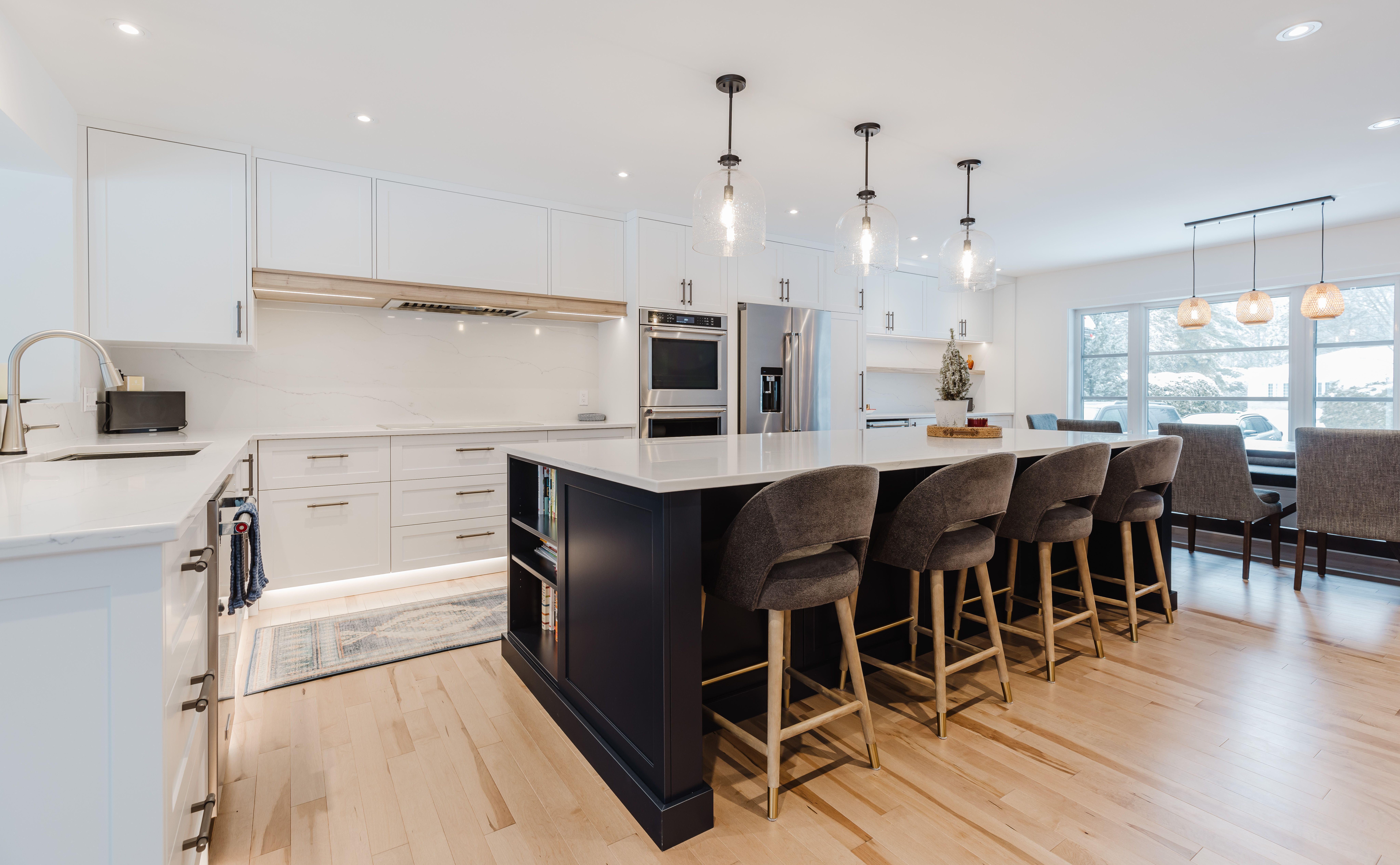 Stylishly designed modern kitchen featuring a spacious island, gray bar stools, and abundant natural light for a bright and inviting atmosphere.
