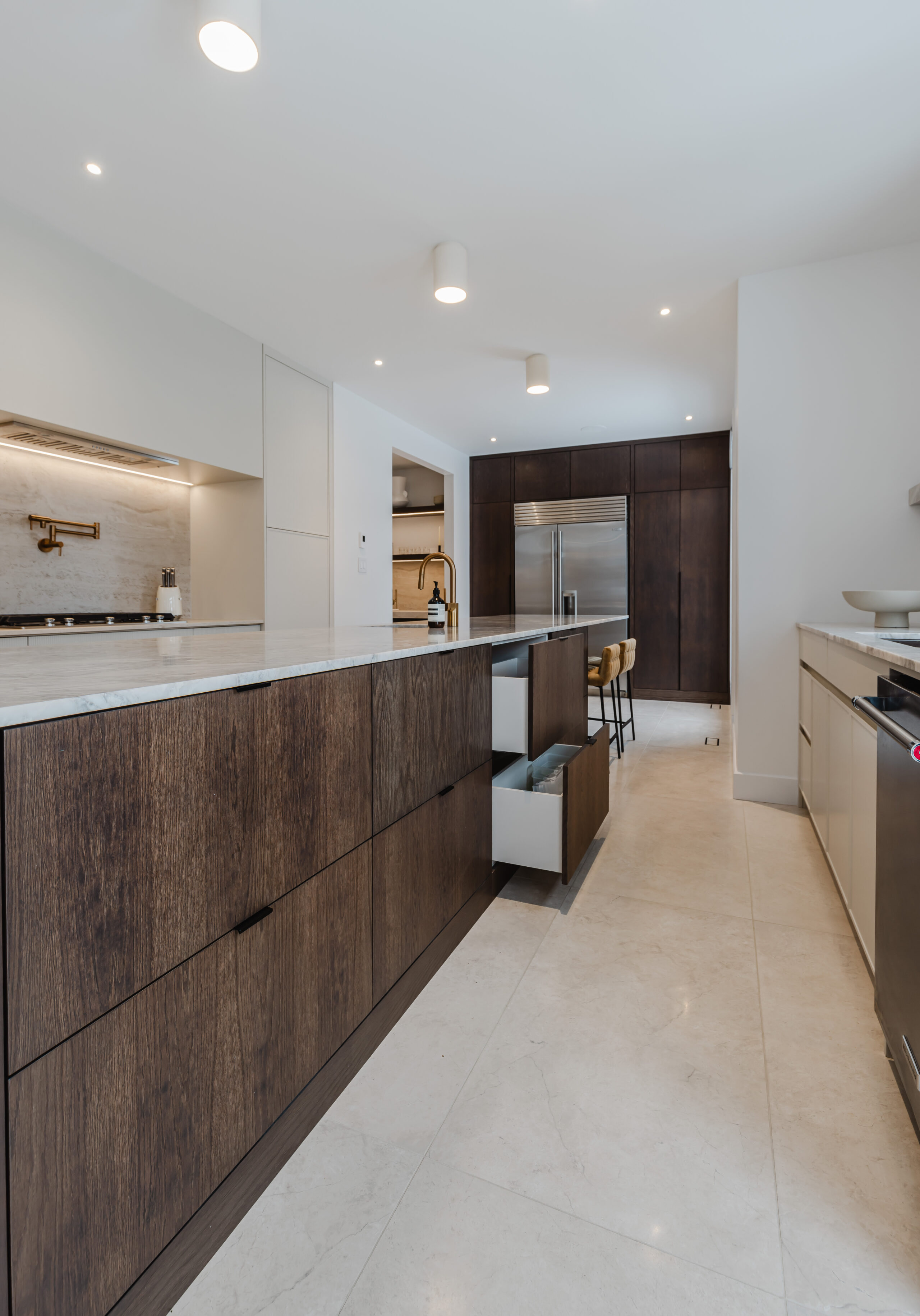 Elegant modern kitchen with a sleek island, rich cabinetry, and inviting bar stools, perfect for social gatherings and dining.