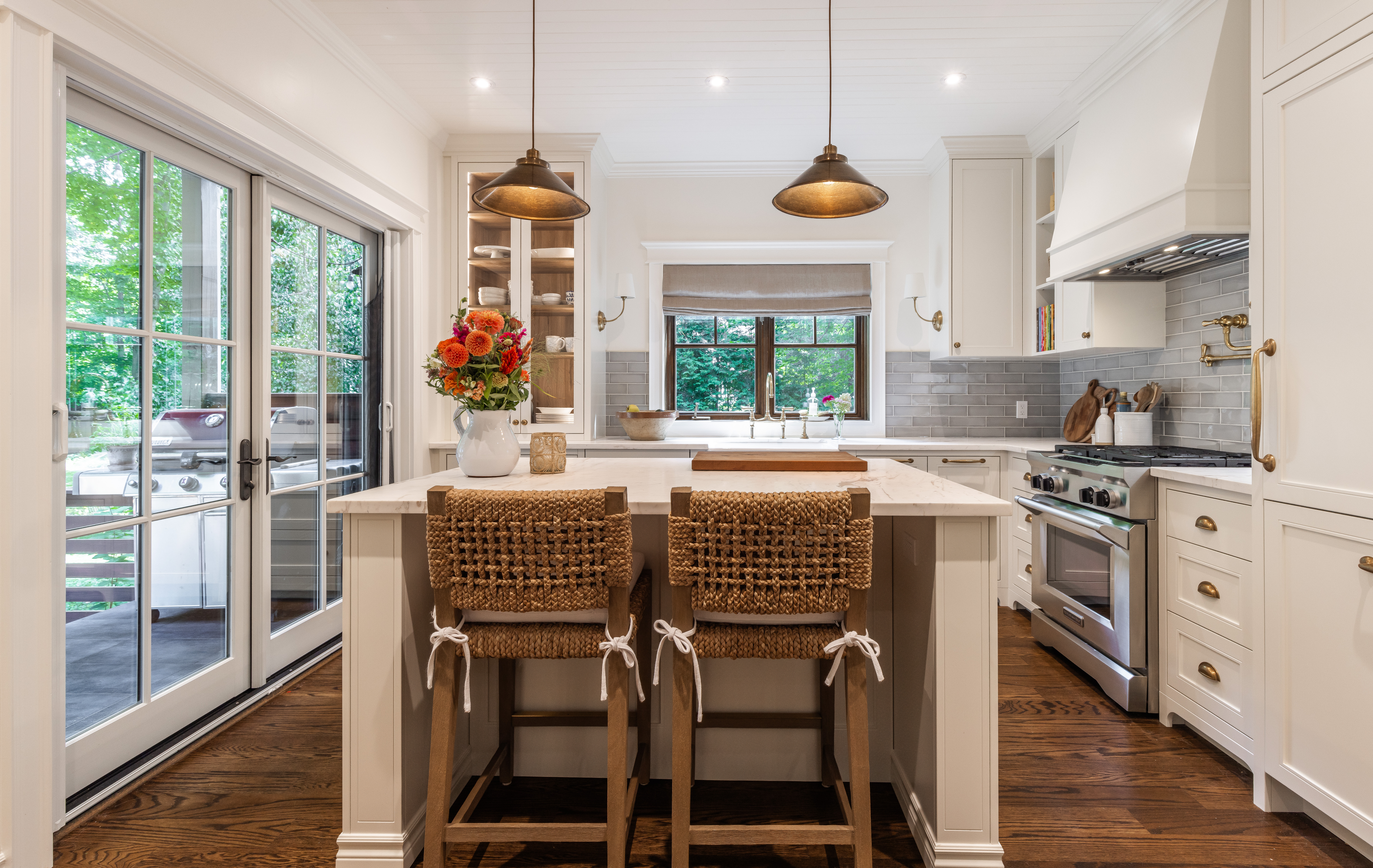 Bright and inviting modern rustic kitchen featuring white cabinetry, a large island, and natural light streaming in through glass doors.