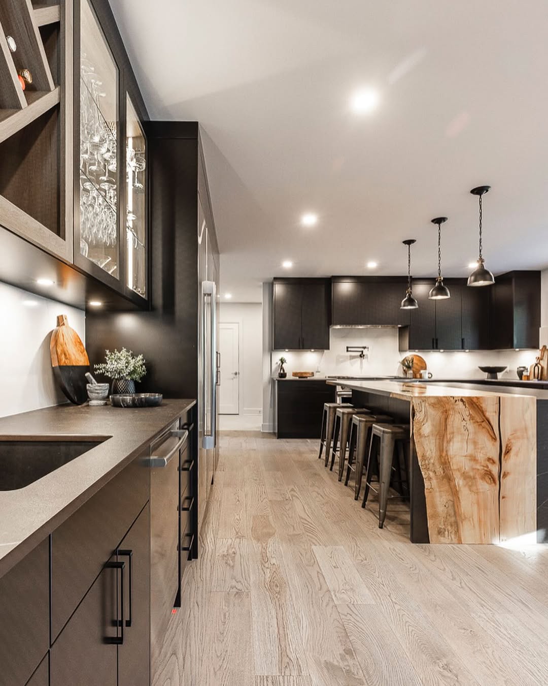 Discover a stylish kitchen featuring dark wood cabinetry, a stunning island, and warm lighting, perfect for hosting and cooking.