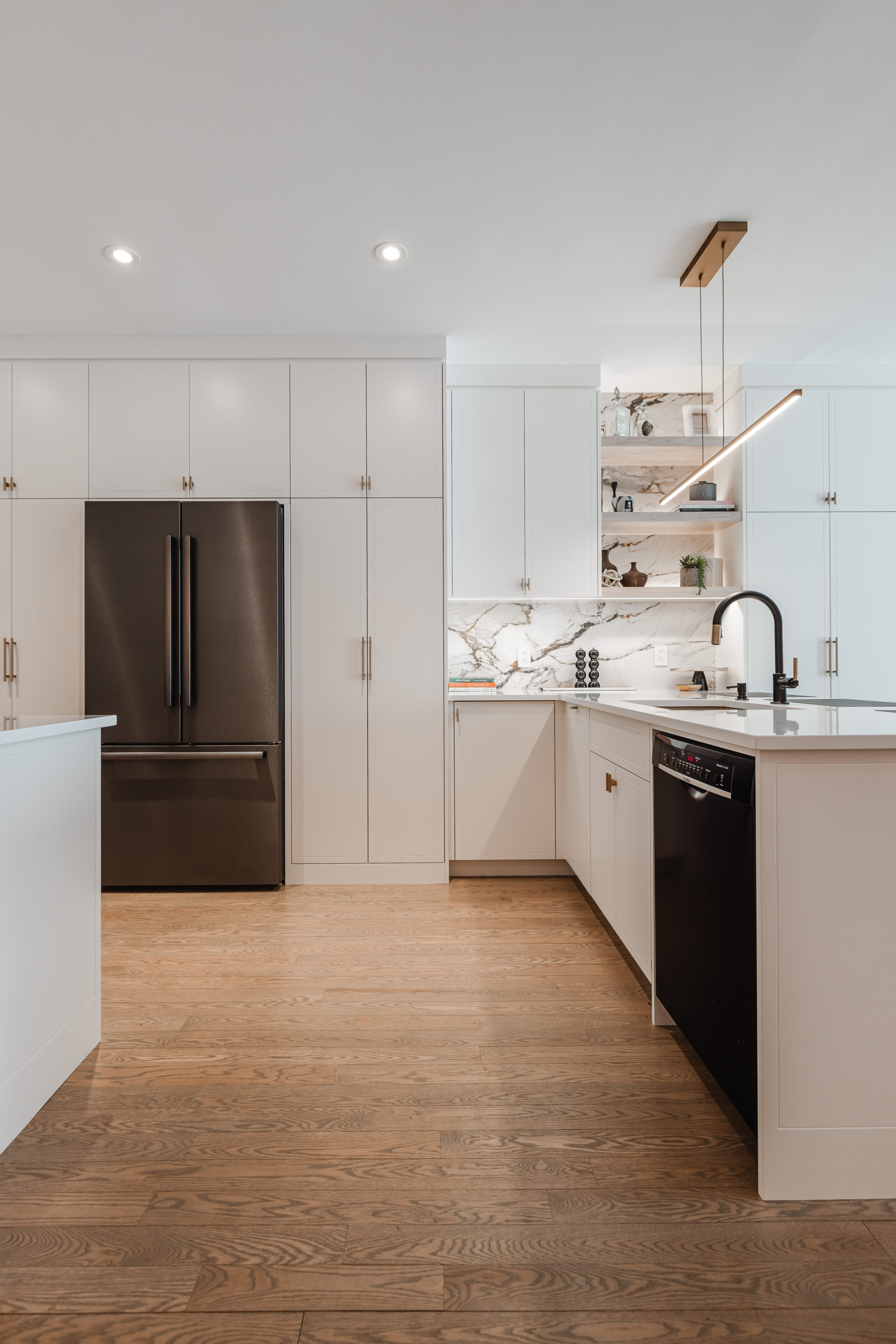 Explore this elegant contemporary kitchen, featuring sleek white cabinetry, warm wood accents, and a striking black countertop, perfect for cooking and entertaining.