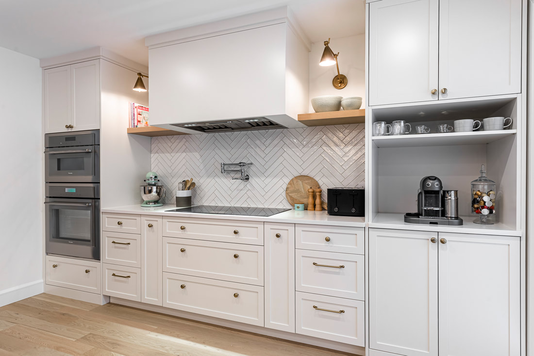 A stunning modern white kitchen features shaker cabinets, brass accents, and a stylish herringbone backsplash, blending elegance and functionality.