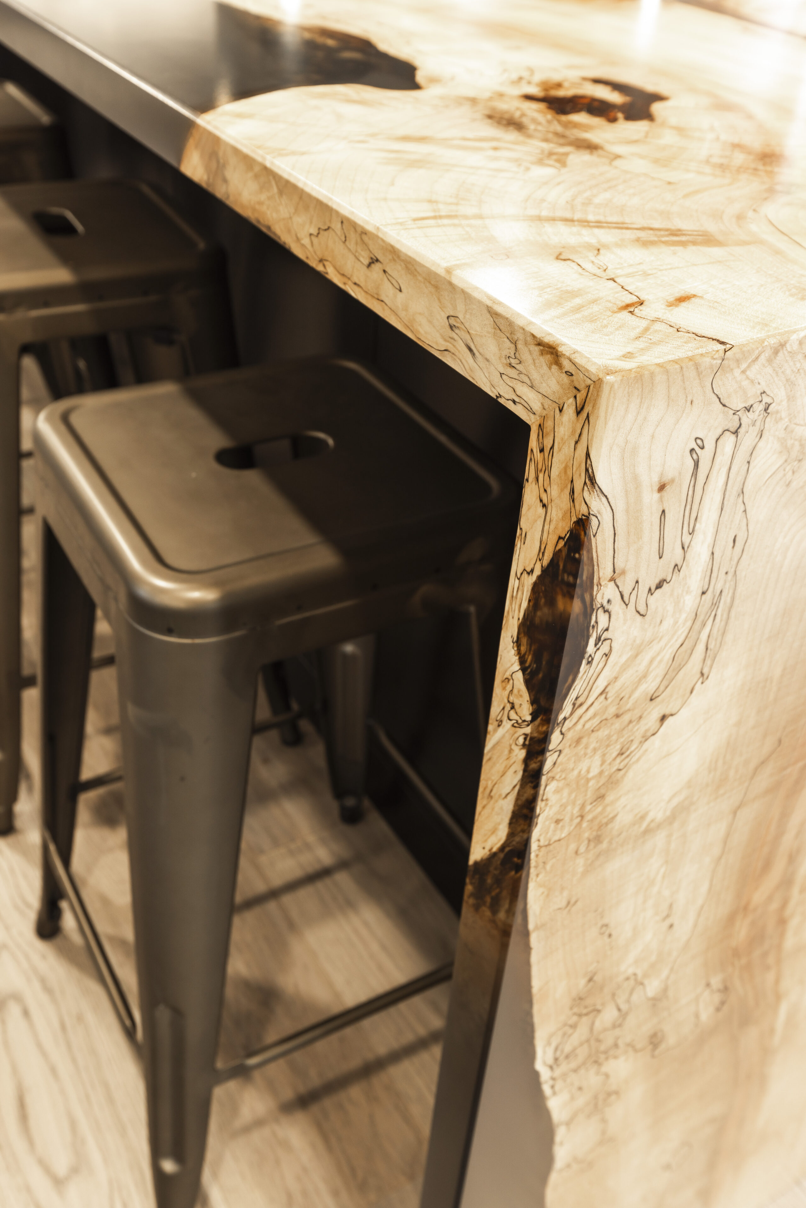Stylish wood bar countertop with a live edge paired with sleek black industrial stools creates an inviting social space.