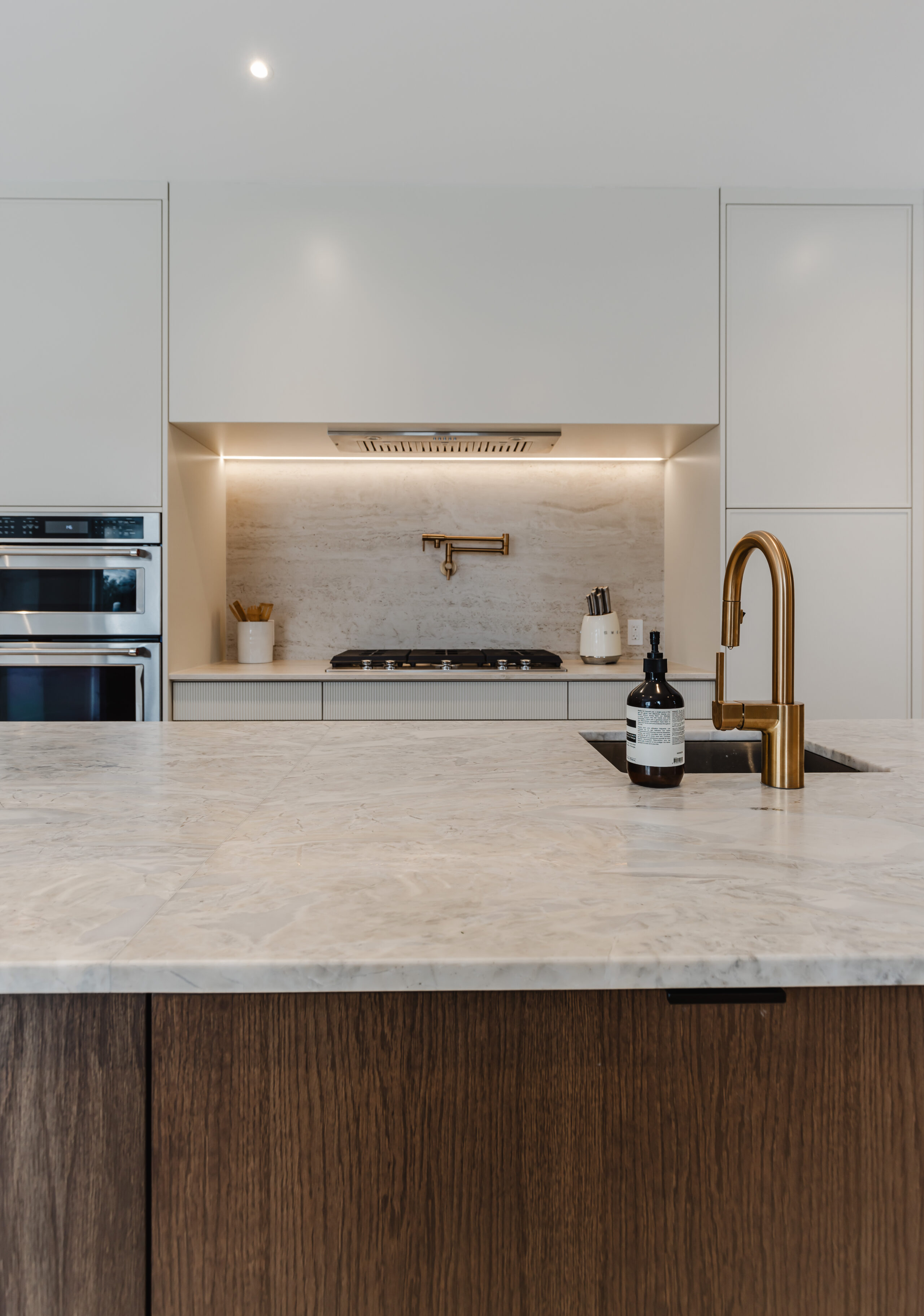Explore this modern minimalist kitchen featuring a sleek island, contrasting cabinetry, and elegant gold faucet accents for a stylish culinary experience.