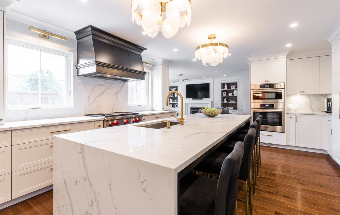 Experience sophistication in this modern kitchen with a luxurious marble island, gold accents, and a warm wood floor.