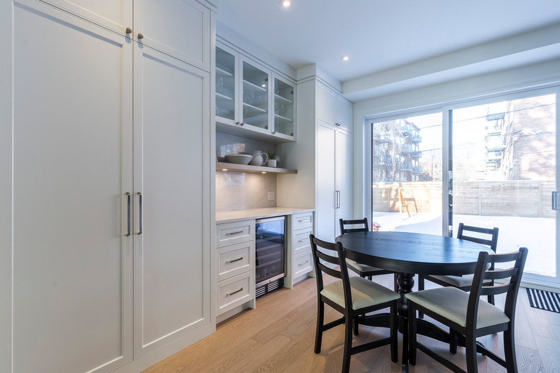 Bright and inviting modern kitchen with white cabinetry, a stylish dark dining table, and abundant natural light flowing in from outside.